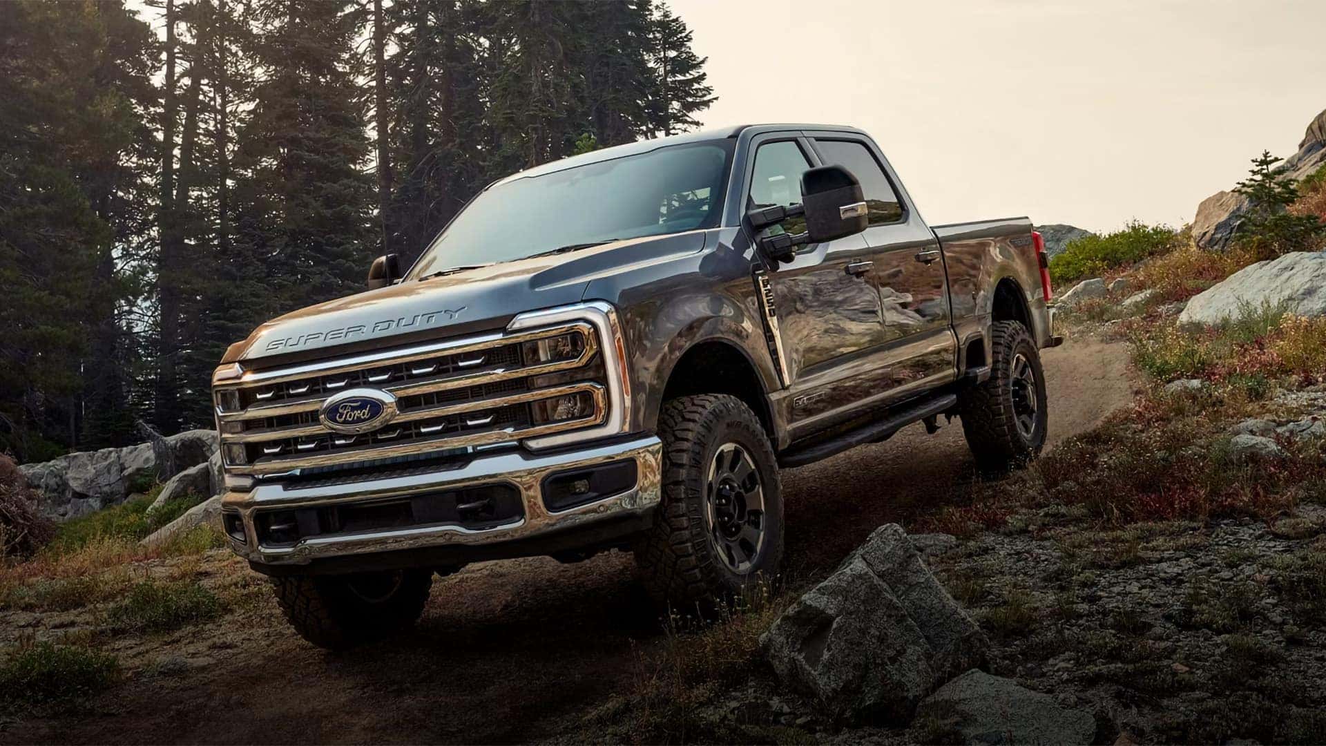 2026 Ford F-350 Super Duty driving off-road on a rocky trail, highlighting rugged suspension, chrome grille, and heavy-duty capability