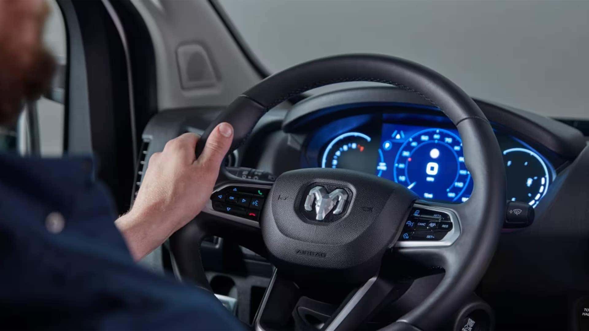 Driver holding steering wheel inside 2026 RAM ProMaster Cargo Van with illuminated digital instrument cluster display