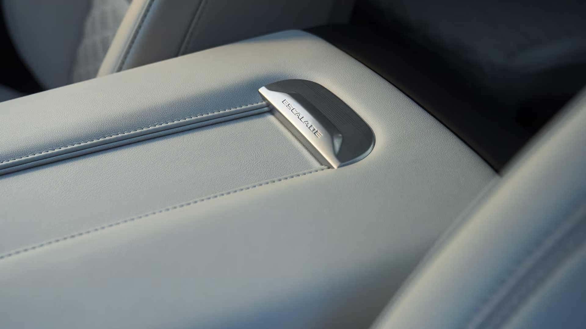 Escalade badge on a light leather armrest with visible stitching inside the cabin