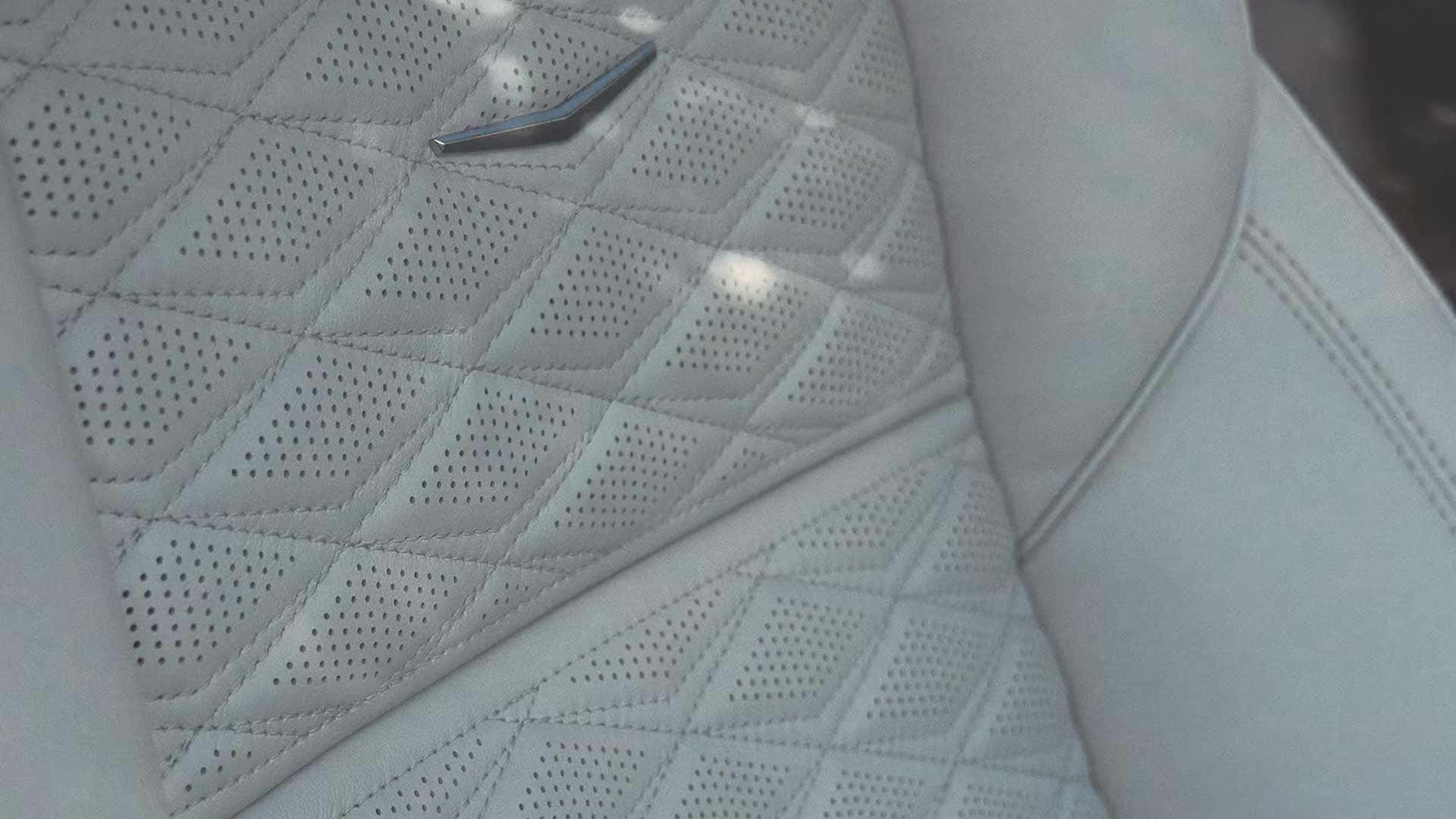 Close up of light leather seat upholstery with perforated diamond stitching and chrome accent