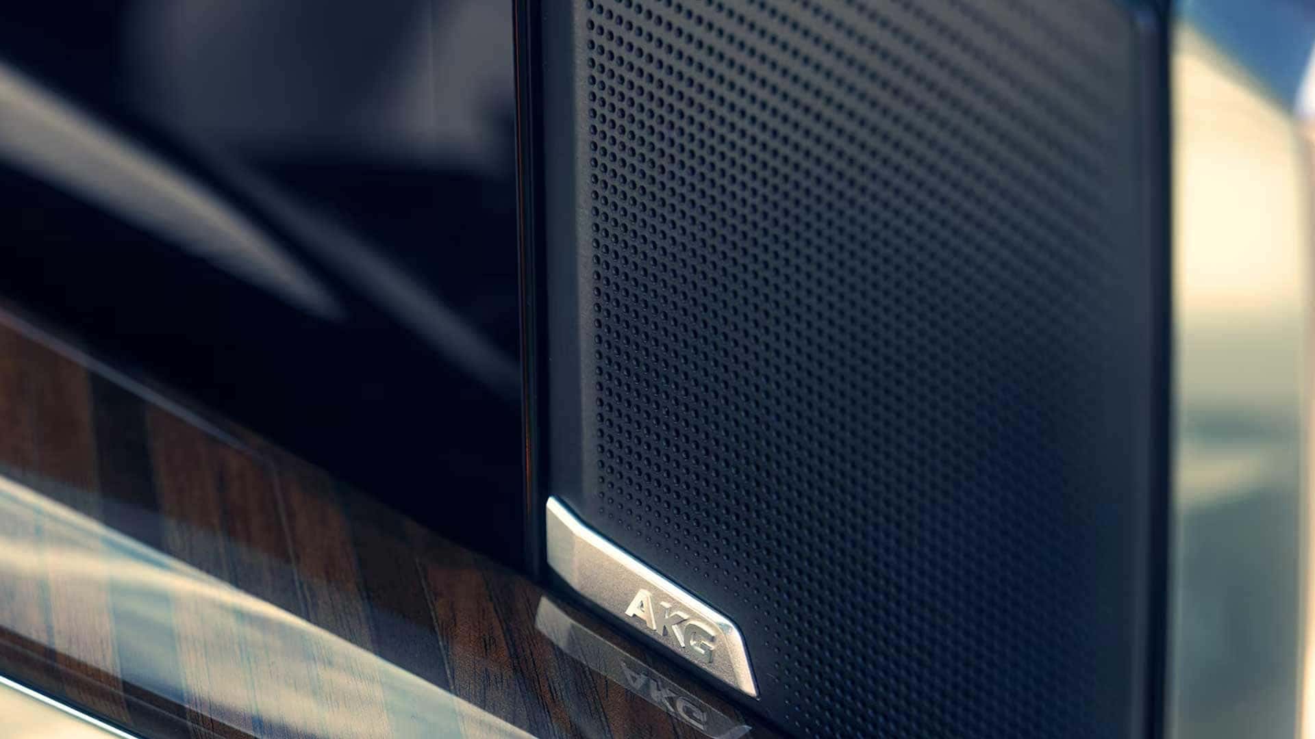 Close up of an AKG speaker grille beside wood trim inside a Cadillac Escalade cabin