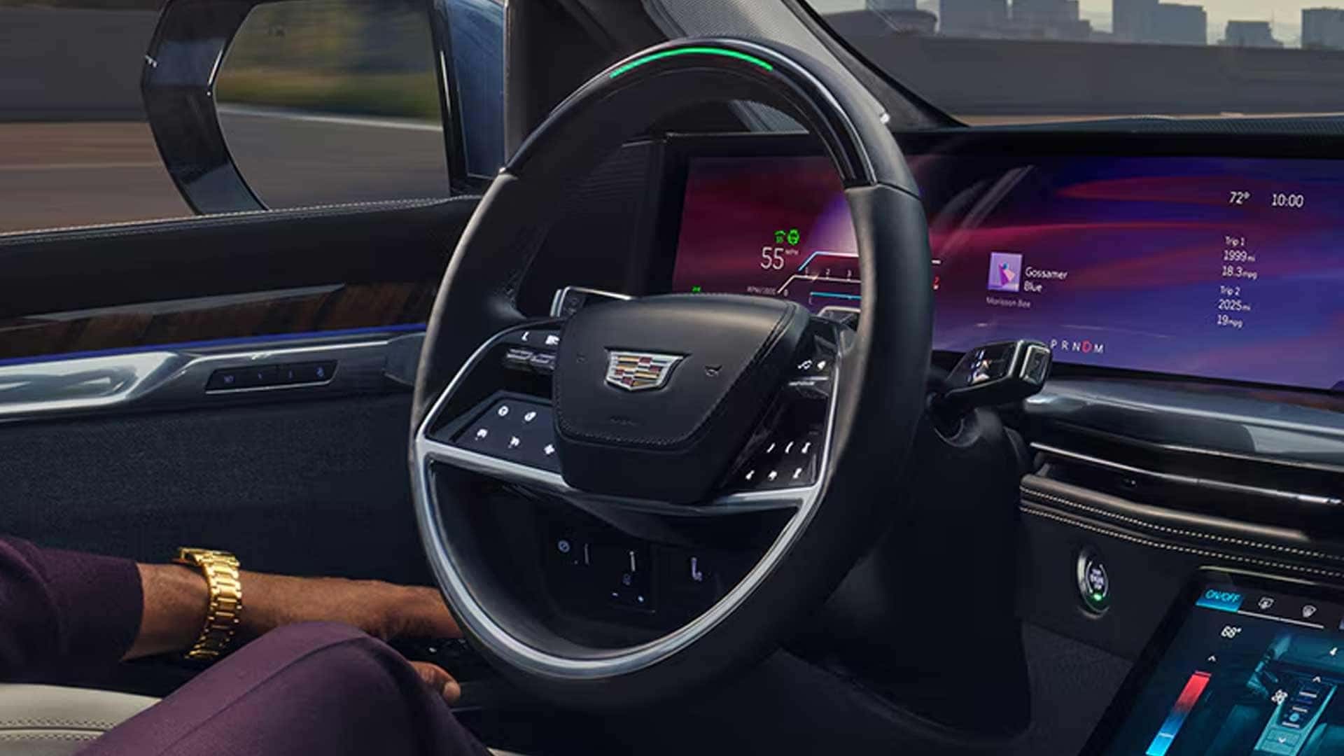 Driver seat view with hands off wheel, green indicator on steering wheel, and digital display showing speed and trip info