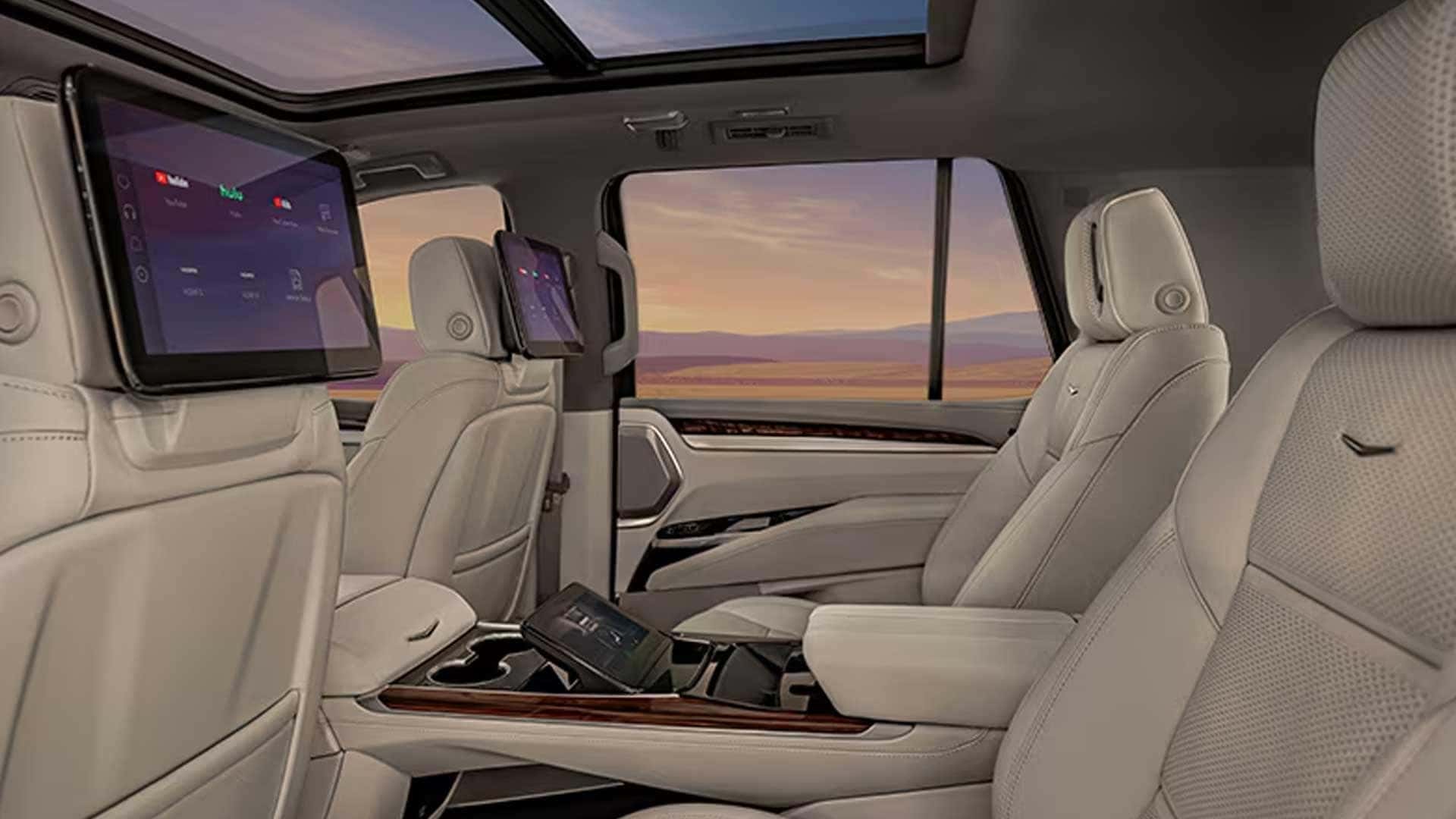 Rear cabin with two captain’s chairs, dual seatback screens, center console controls, and panoramic glass roof