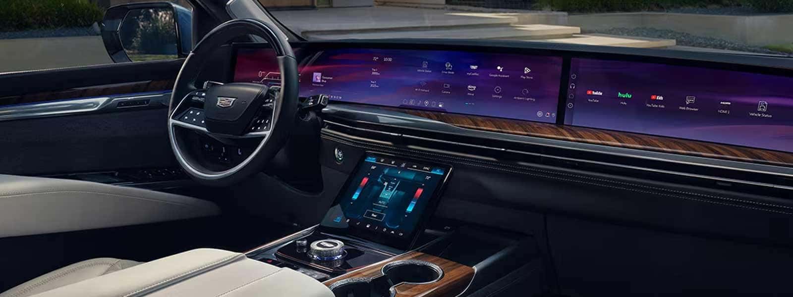 Wide interior shot showing steering wheel, large curved display across dashboard, and center console controls