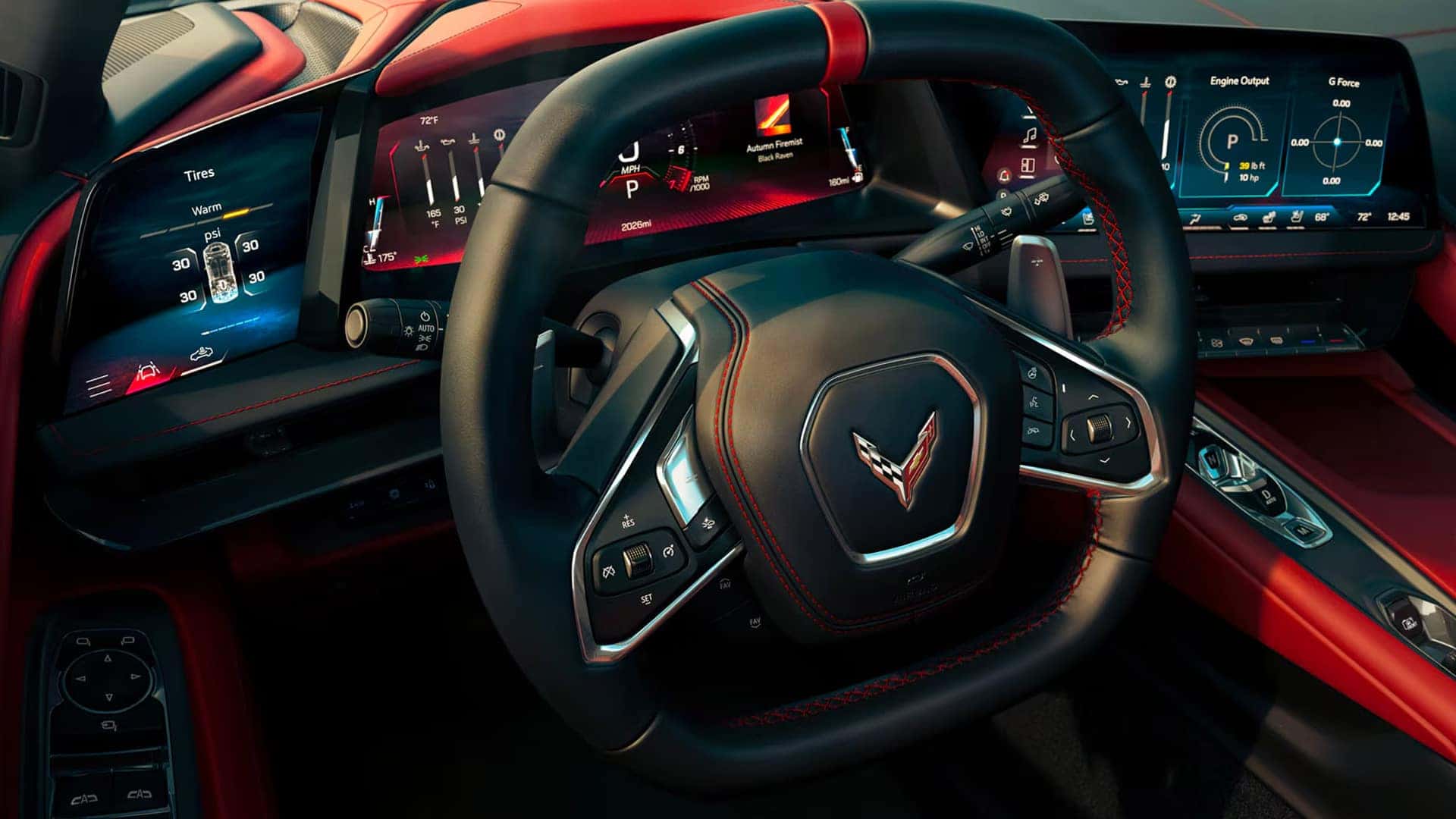 Driver view of a Stingray cabin with steering wheel, digital screens, tire data, gauges, and red trim