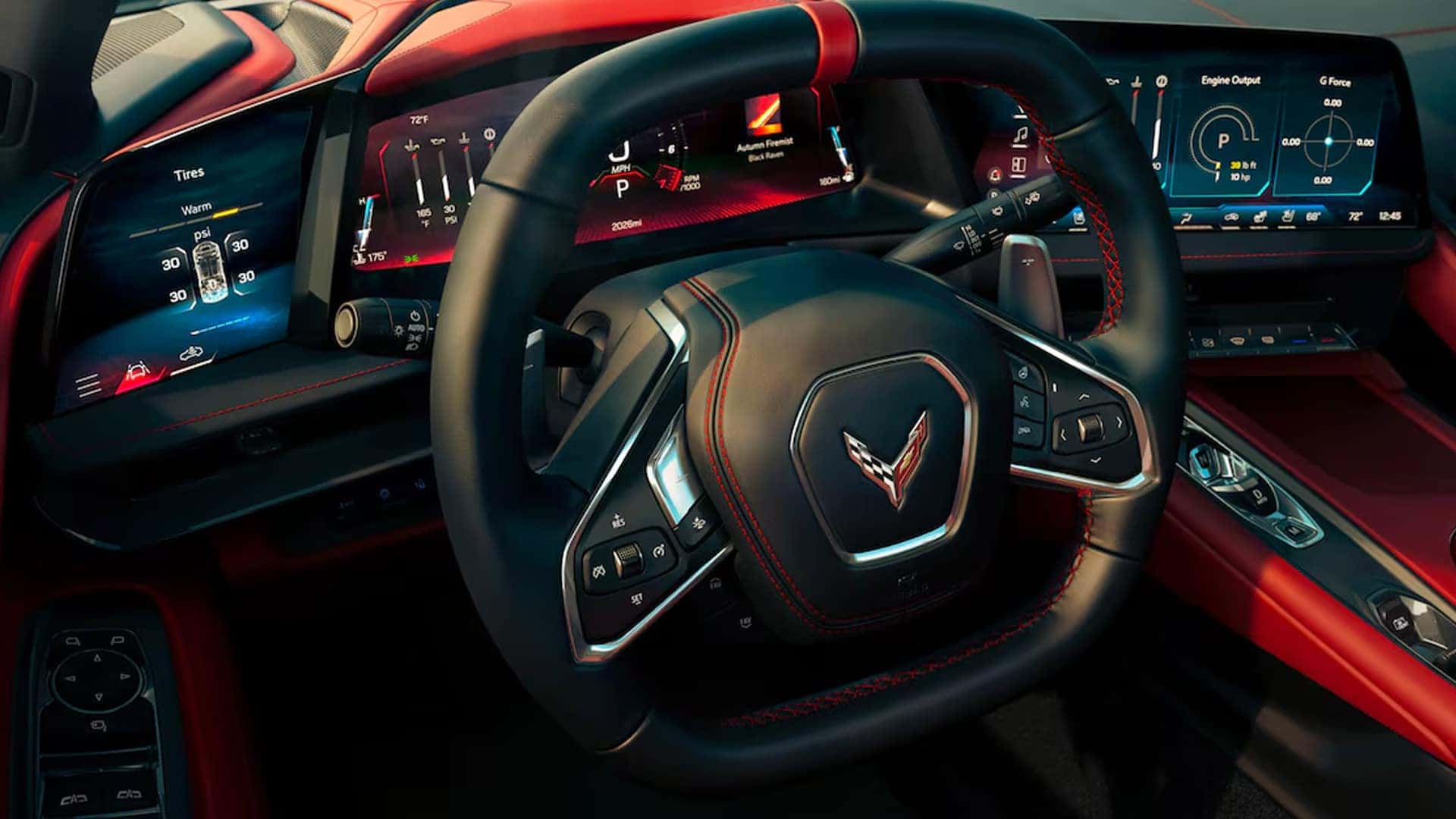 Close-up of Corvette steering wheel with three digital displays showing tire, gauge, and performance data.
