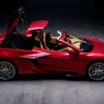 Red Corvette Z06 convertible shown from the side with the roof panels open and a driver inside.