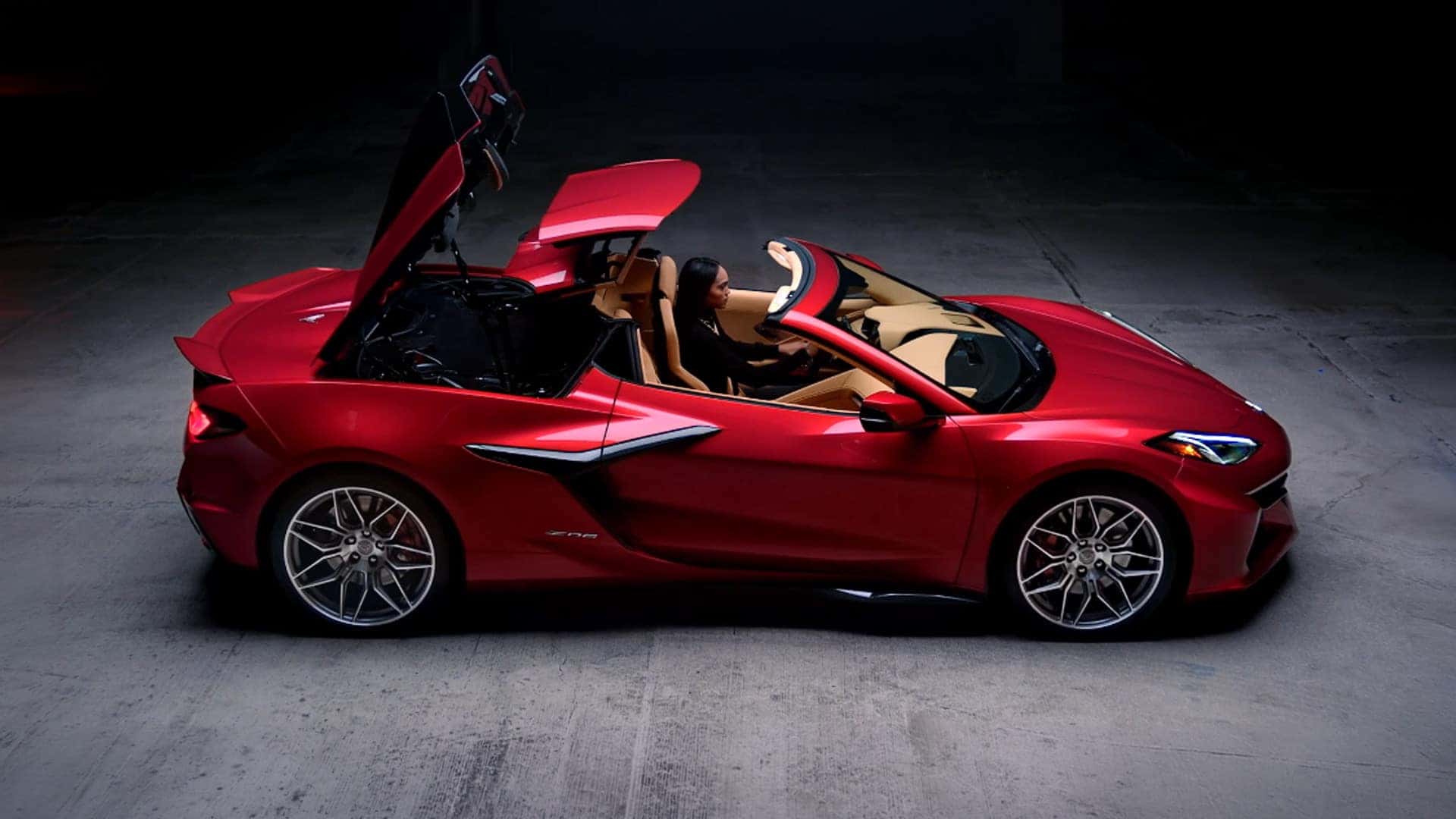 Red Corvette Z06 convertible shown from the side with the roof panels open and a driver inside.