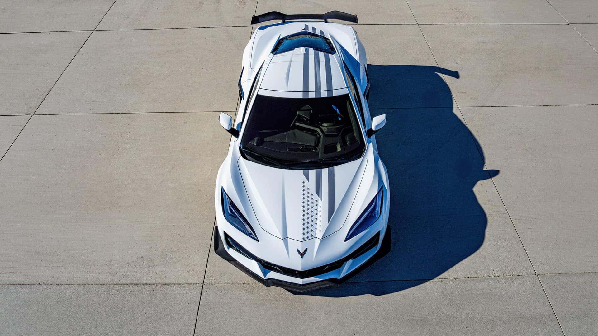 White Corvette shown from above with gray stripes, star graphics, black roof, and large rear wing.