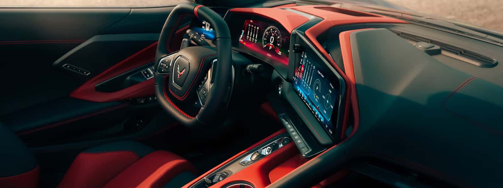 Overhead view of the 2026 Corvette Z06 cockpit showing the steering wheel, digital gauge cluster, center touchscreen, and red interior.