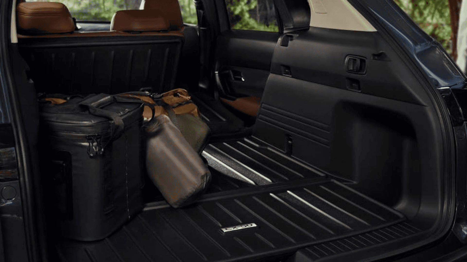 Open rear cargo area of a Mazda CX-50 with bags inside and brown rear seats visible beyond the load floor