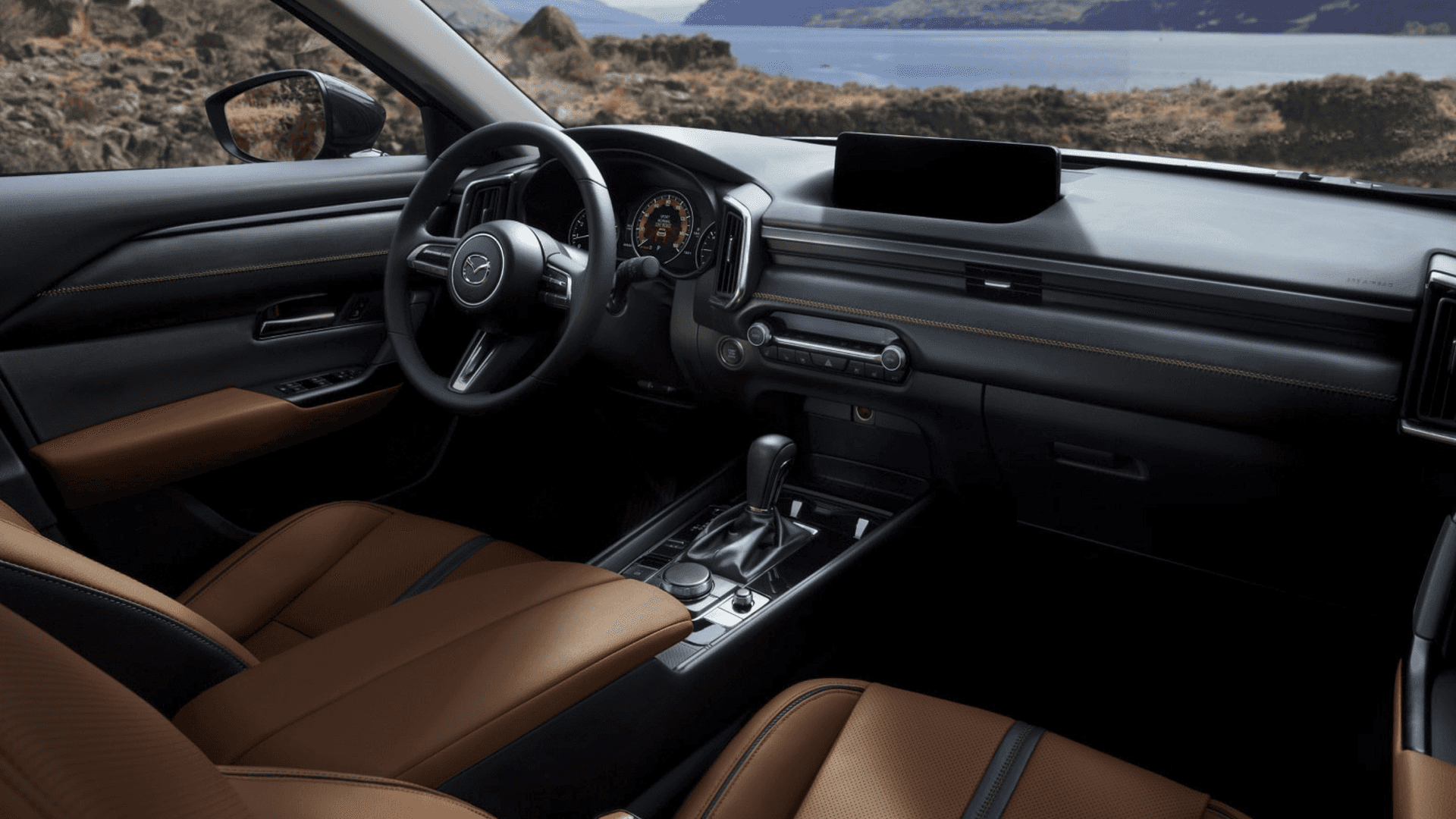 Front cabin view with brown seats, steering wheel, center display, console controls, and water outside the windows