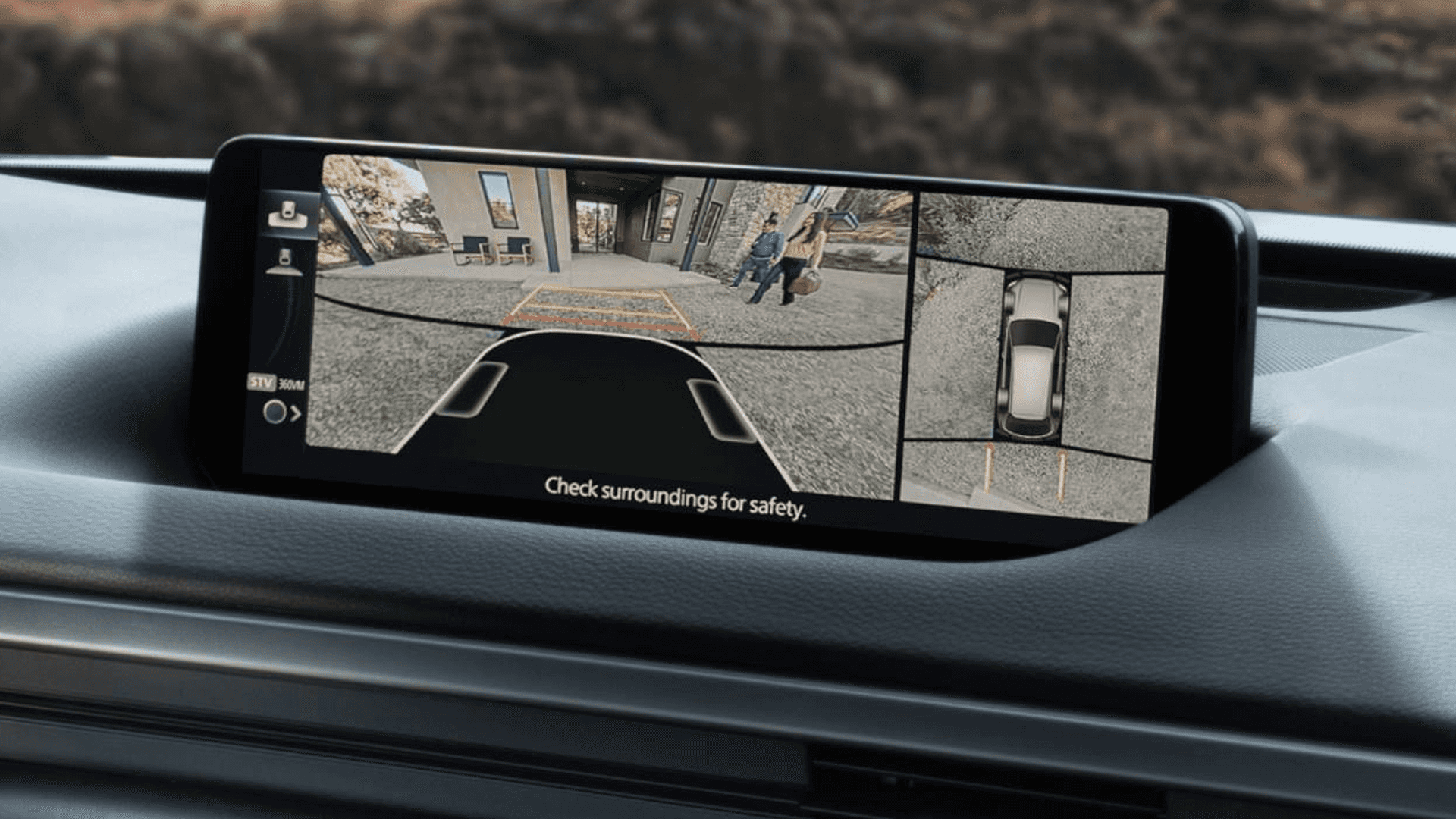 Center display showing a split camera view with rear surroundings and overhead vehicle parking view.