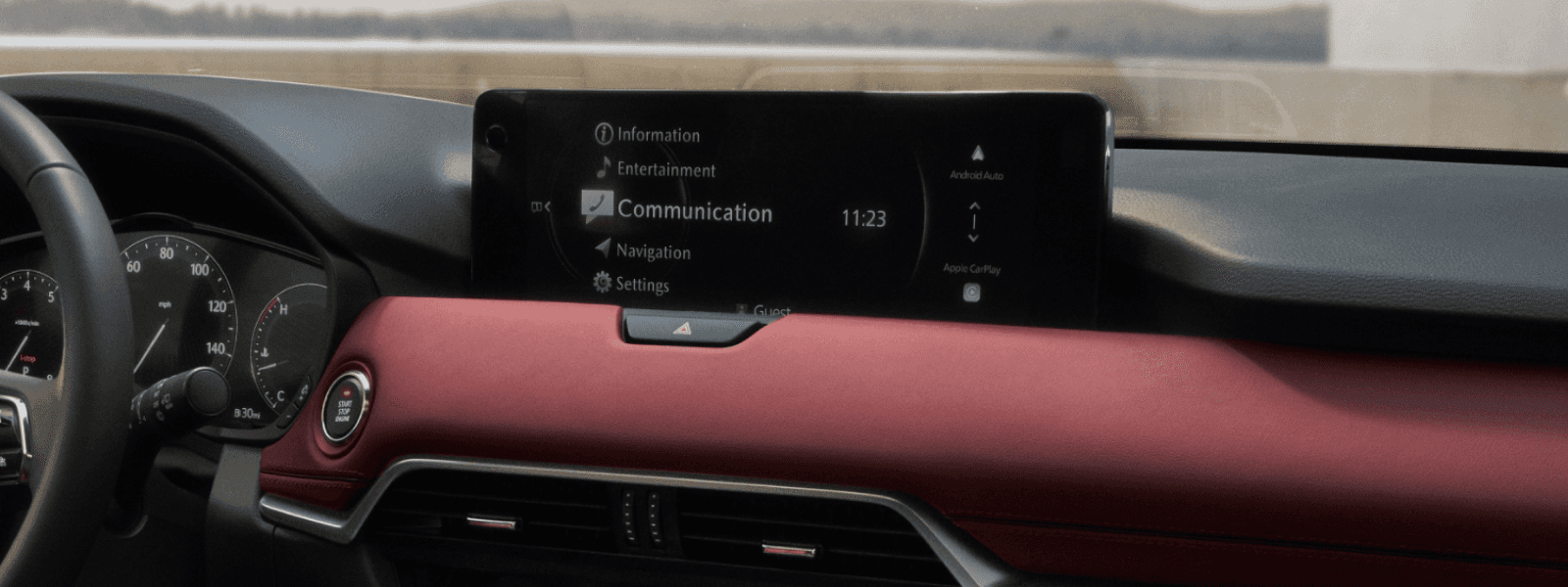 Dashboard interior with wide center display showing menu options like communication and navigation above red trim.