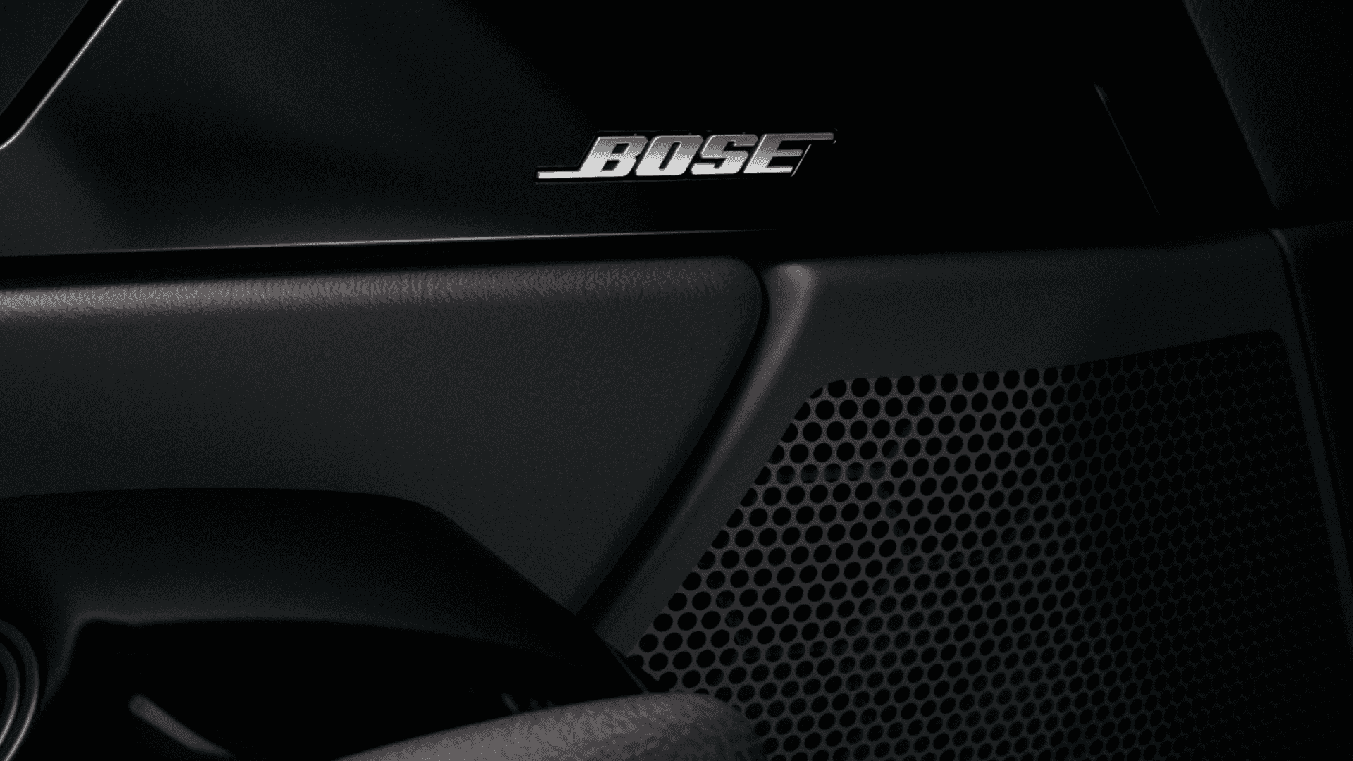 Close-up of Bose speaker grille mounted near the door panel with surrounding black interior trim