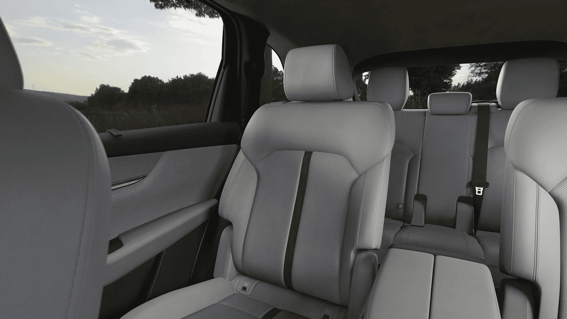 Light-colored rear seating area of Mazda CX-90 showing two rows of seats with headrests and side window view
