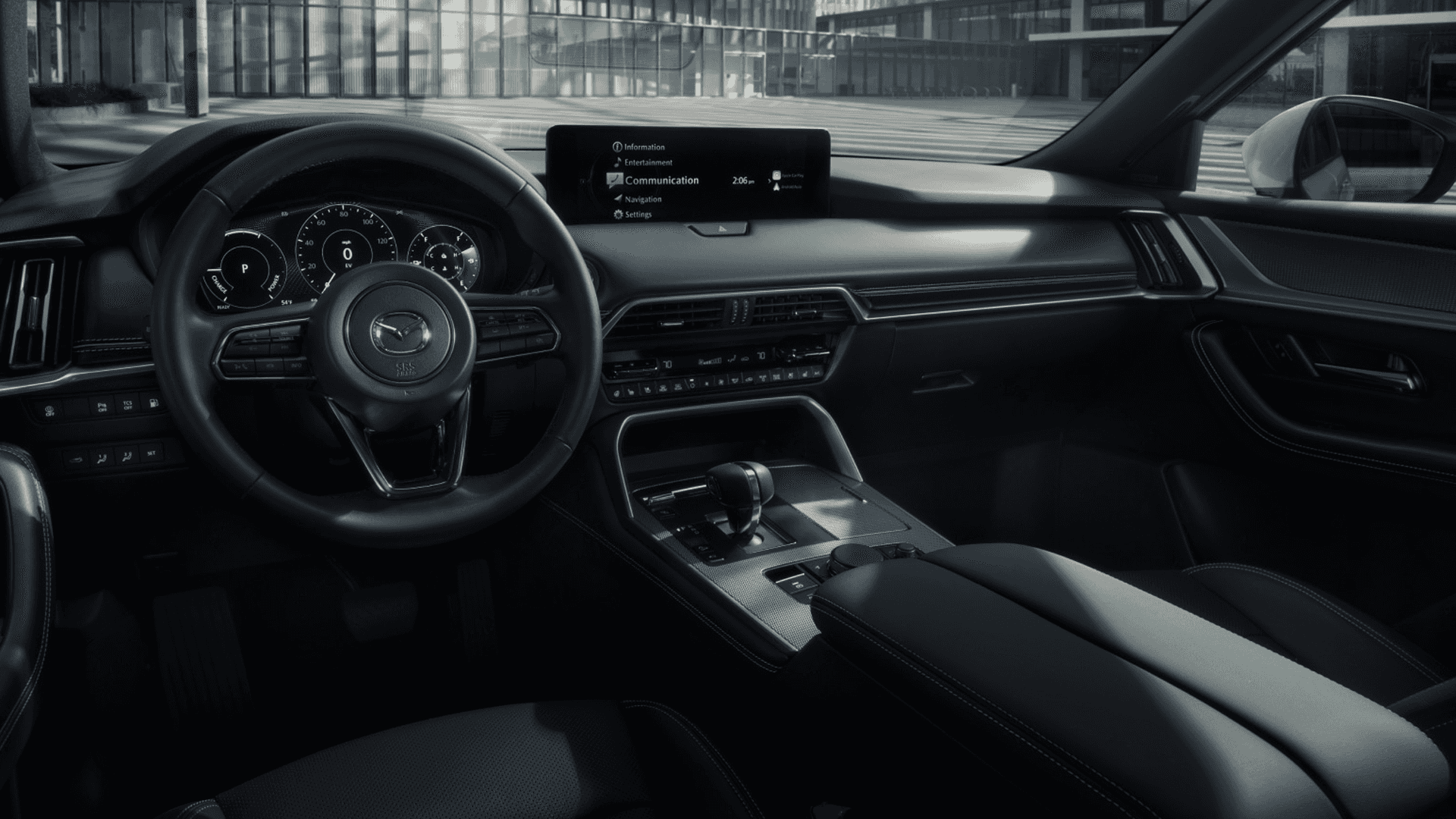 Wide cabin view with driver at the wheel, center display, black dashboard, and front console in motion