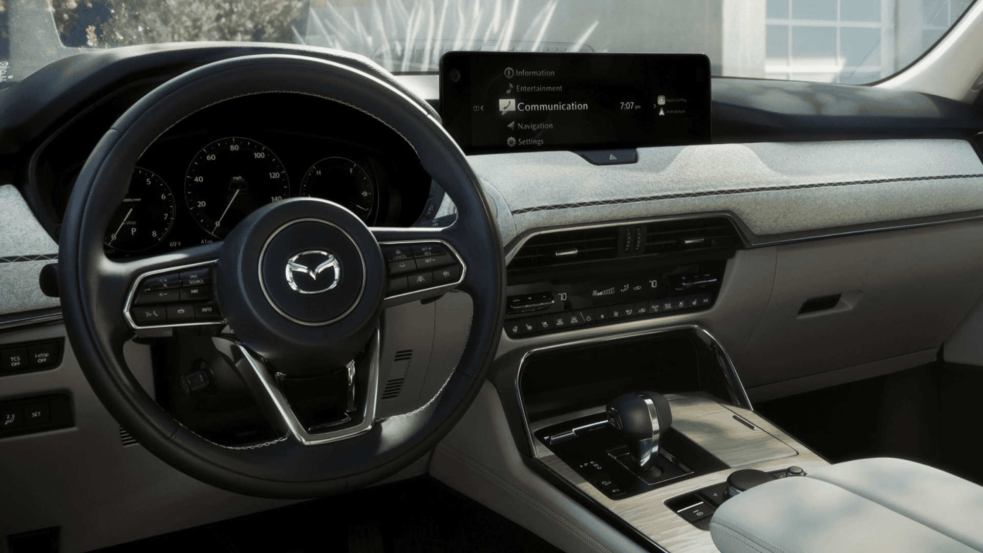 Interior view with steering wheel, center display menu, dashboard controls, and center console with gear selector.