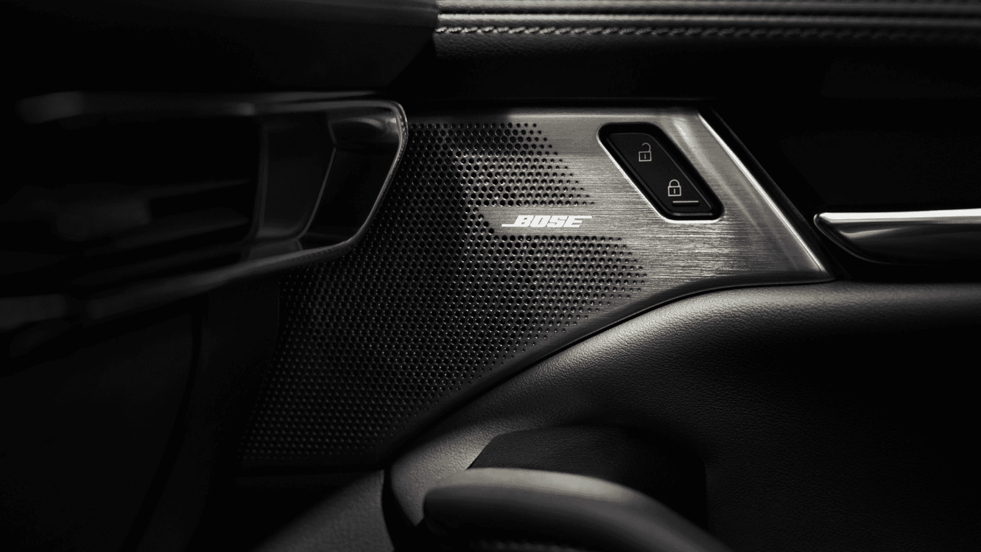 Close-up of Bose speaker grille in Mazda3 door panel with metallic finish and lock controls beside speaker