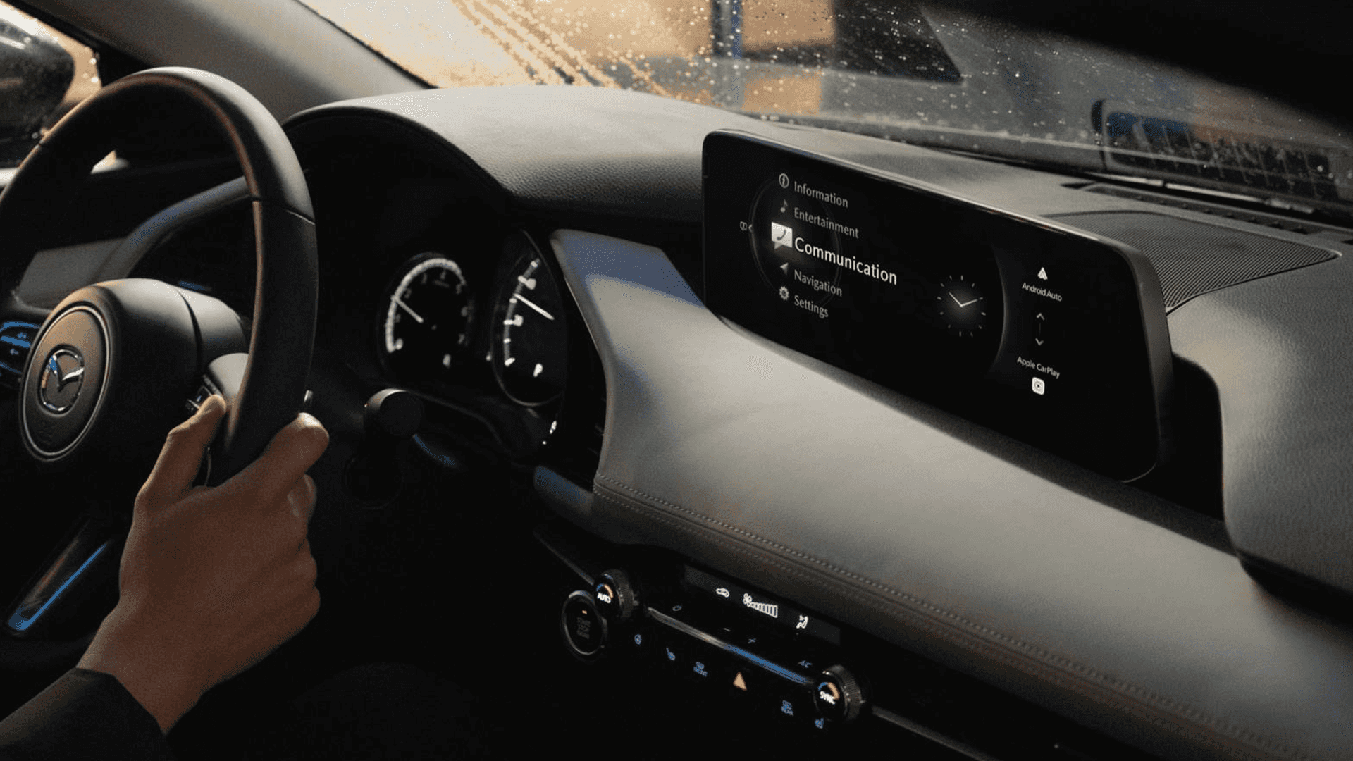 Mazda3 dashboard with wide infotainment display showing communication menu and smartphone connection icons.