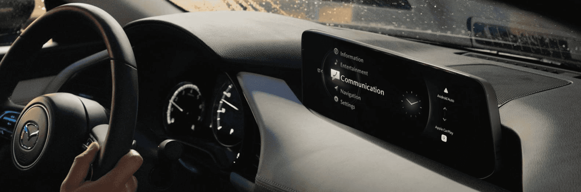 Wide view of Mazda3 interior with slim dashboard screen displaying communication menu and phone connectivity icons.