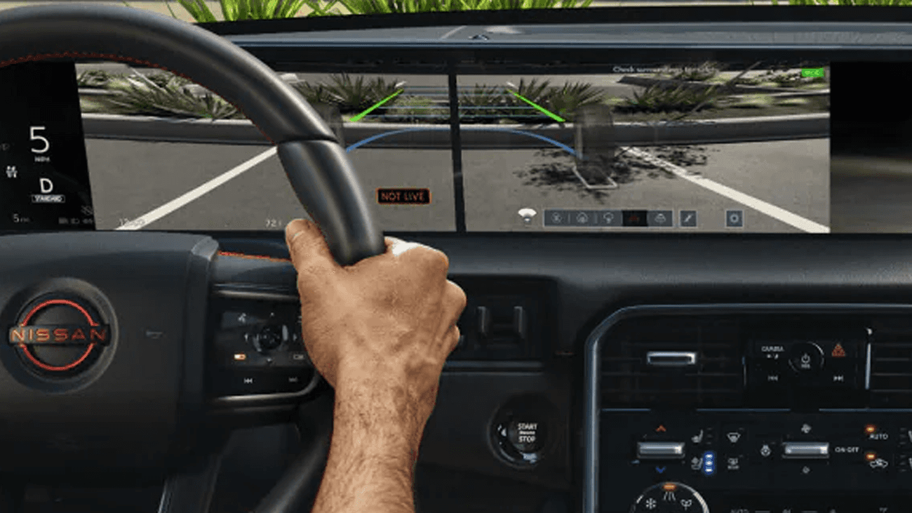 Driver’s perspective showing steering wheel and dual-screen display with parking camera and guidance lines