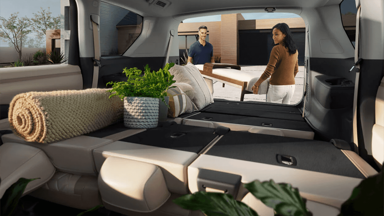 Folded rear seats creating flat cargo space while two people load furniture into the back of the SUV