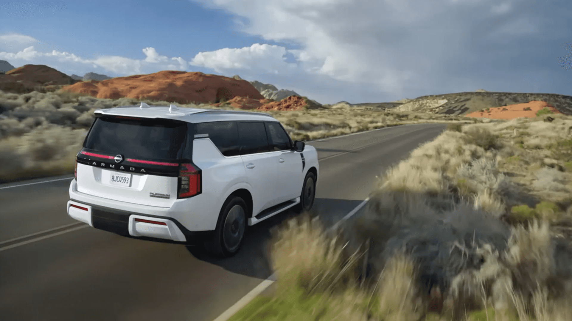 White Nissan Armada driving on a desert road with rear LED light bar visible and hills in the background