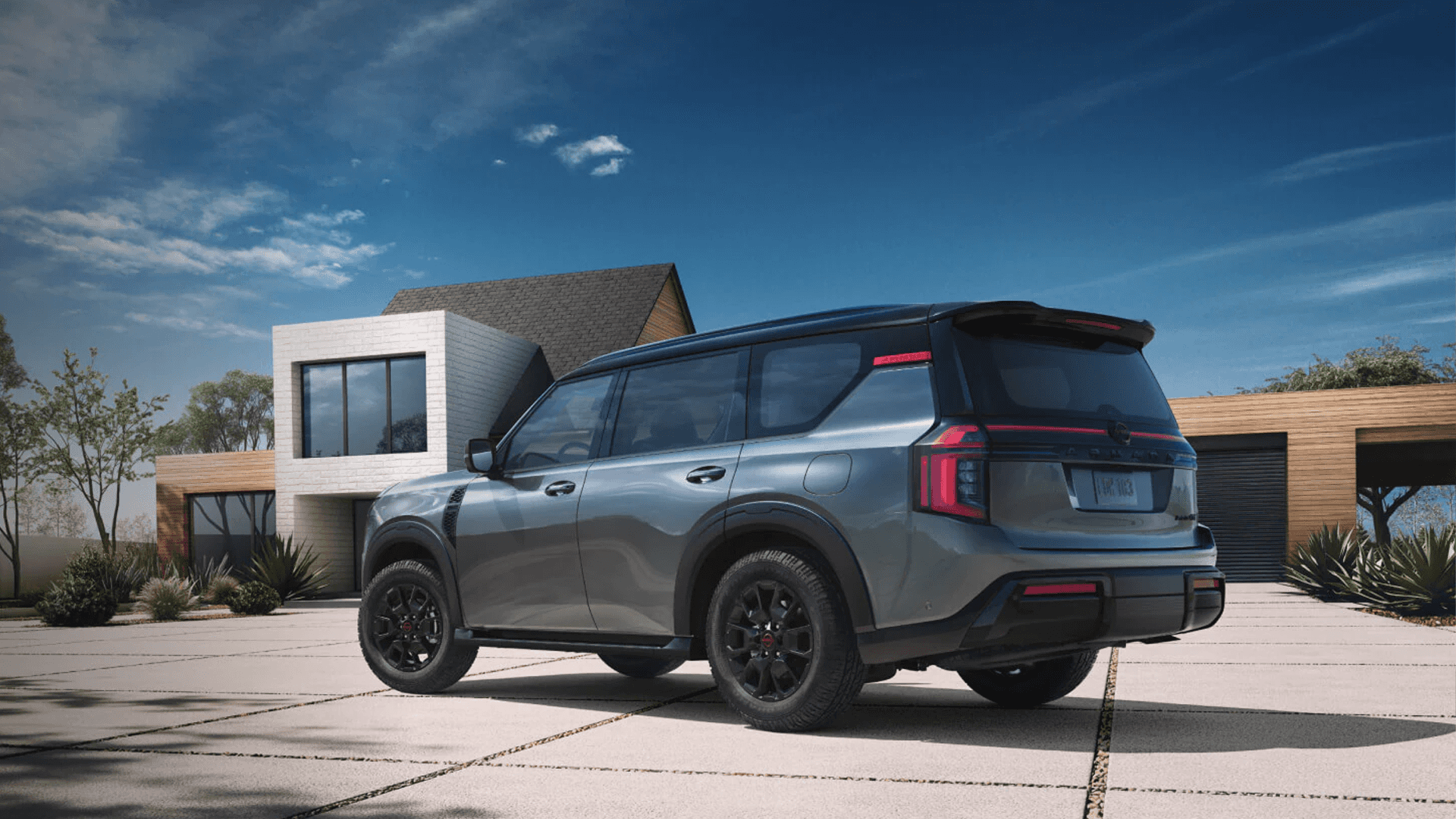 Gray Nissan Armada parked on a concrete driveway in front of a modern home with clean architectural lines