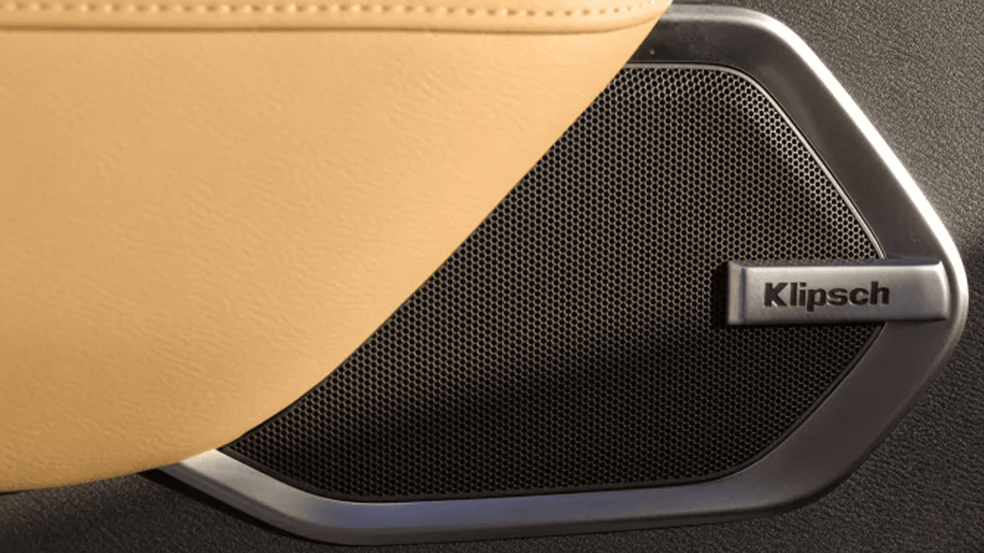 Close-up of door-mounted speaker with Klipsch badge and textured grille integrated into tan interior panel
