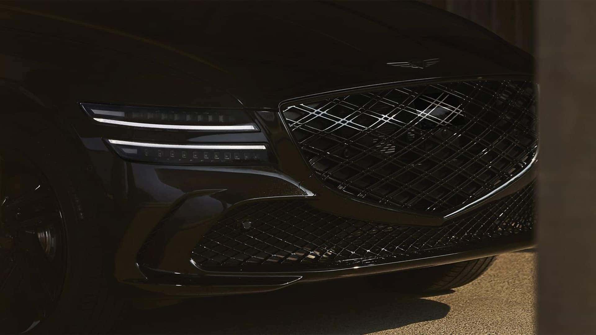 Front view of 2026 Genesis G80 showing crest grille and signature two-line LED headlights in low light