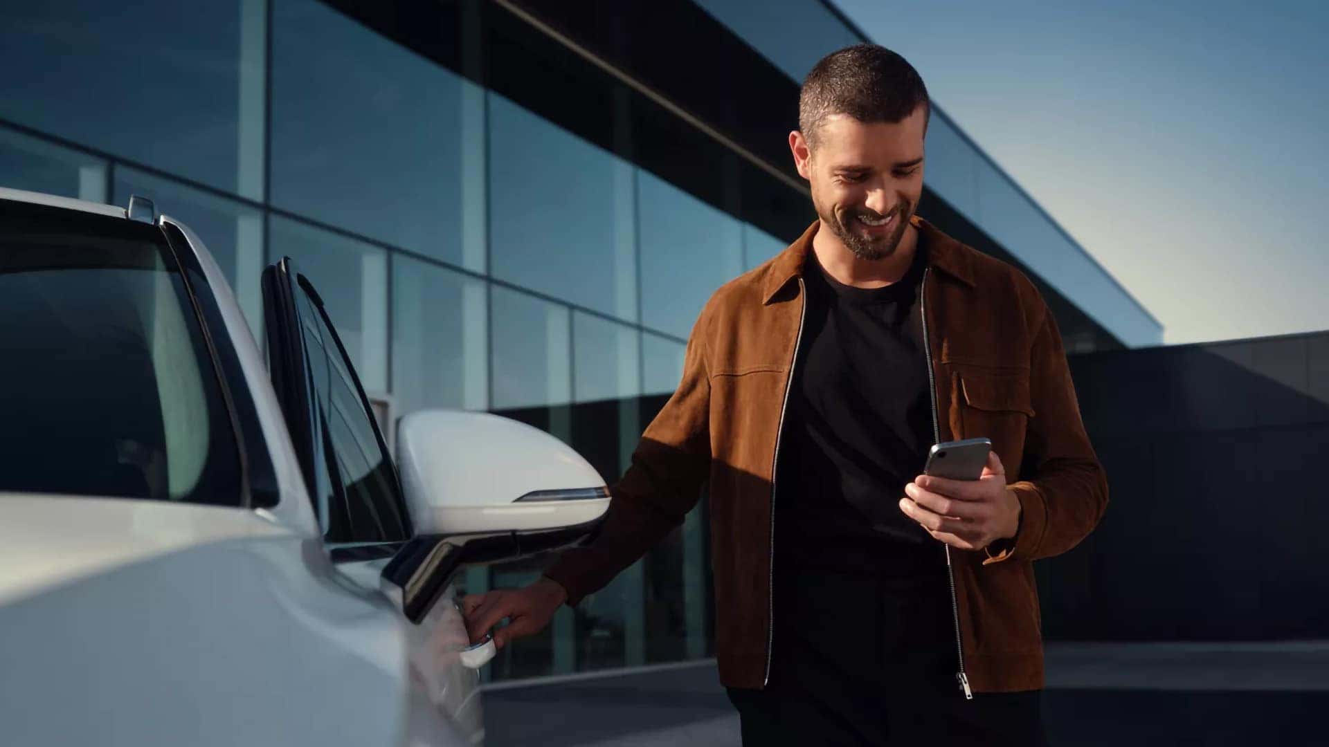 Driver using smartphone with Genesis Digital Key near 2026 Genesis G80 for remote access and connected features