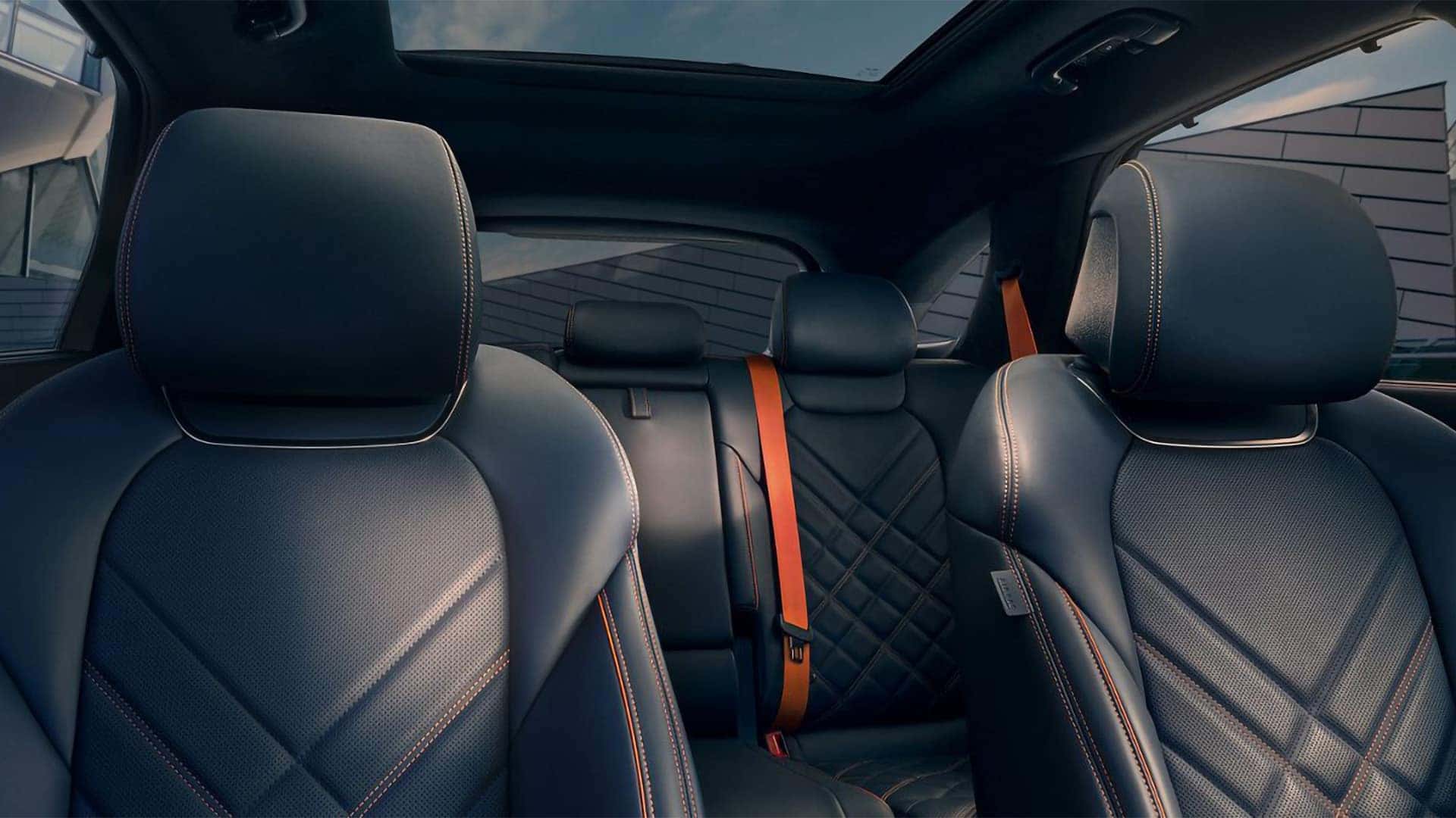 2026 Genesis GV70 interior with black leather seats, panoramic sunroof, and rear passenger seating area