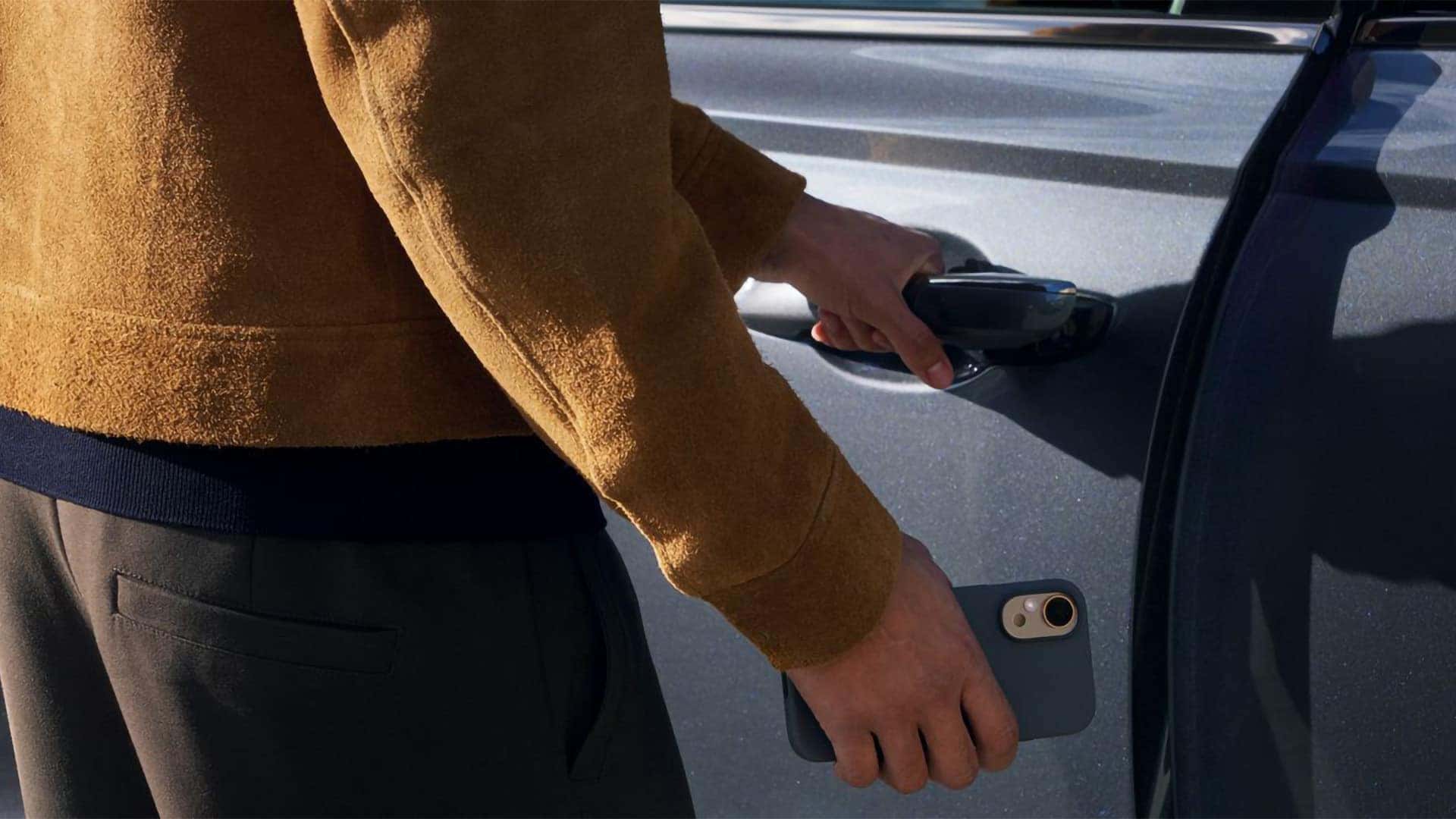 2026 Genesis GV70 Digital Key 2 access with driver holding a smartphone near the vehicle door handle