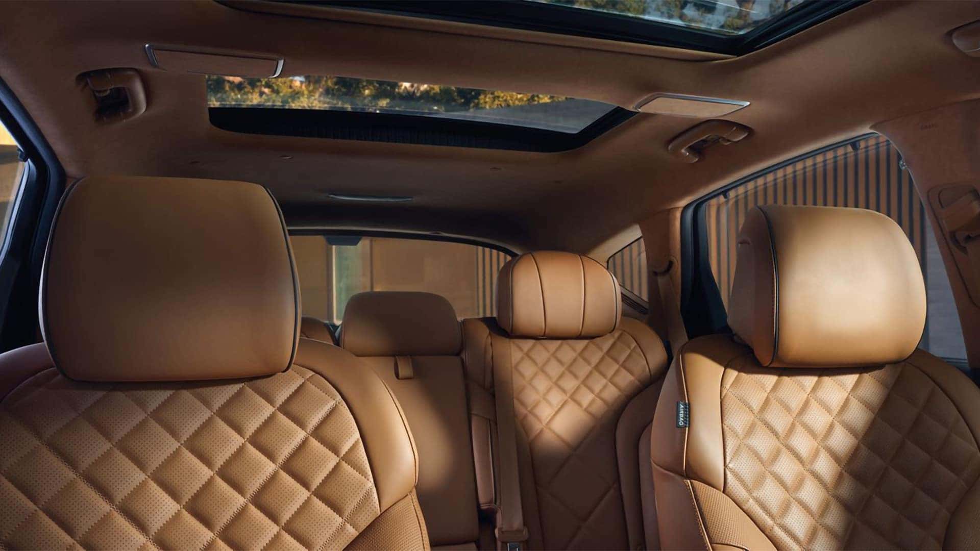2026 Genesis GV80 interior with quilted leather seats and panoramic sunroof letting in natural light