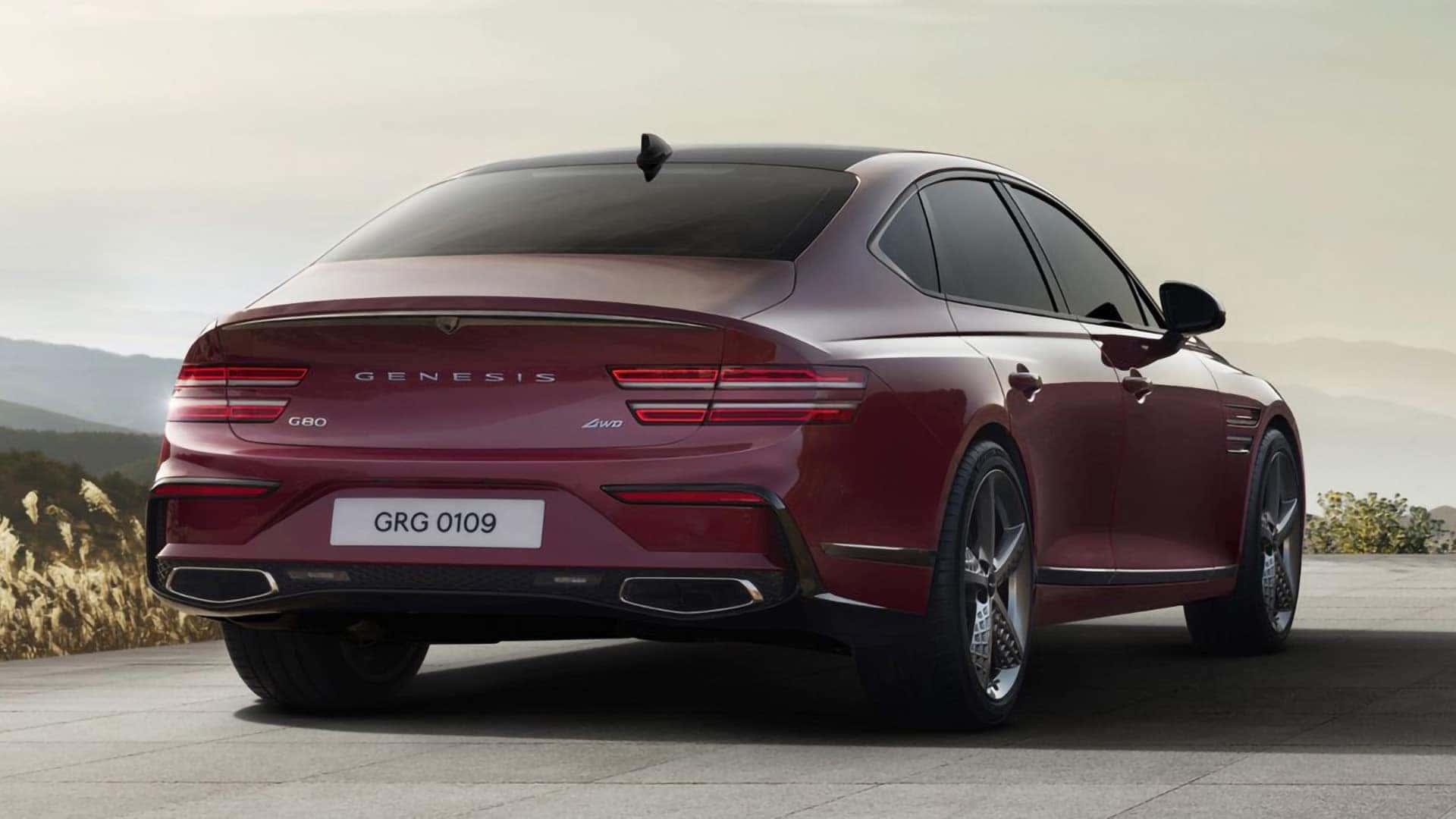 Rear three quarter view of red 2026 Genesis G80 with two-line LED tail lights and dual exhaust outlets