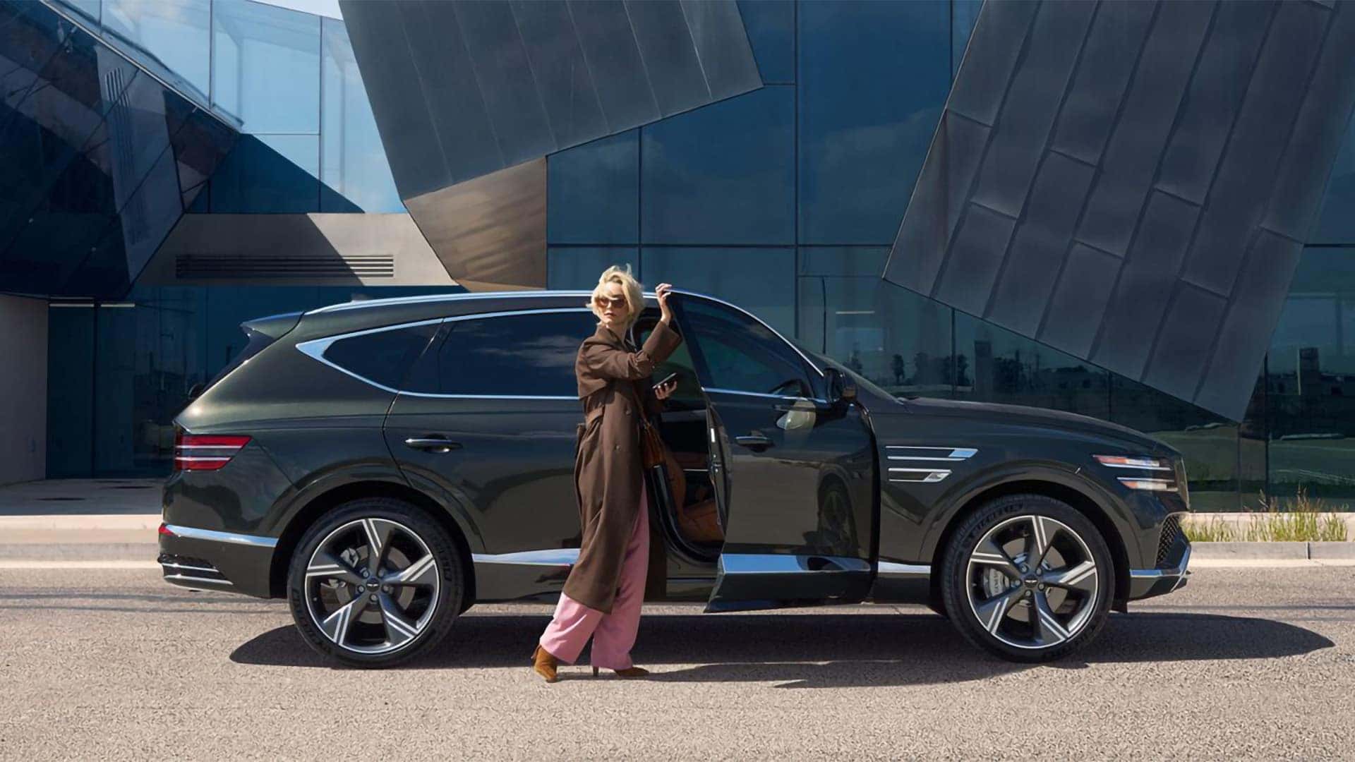2026 Genesis GV80 side profile with driver standing by open door highlighting luxury SUV proportions and design