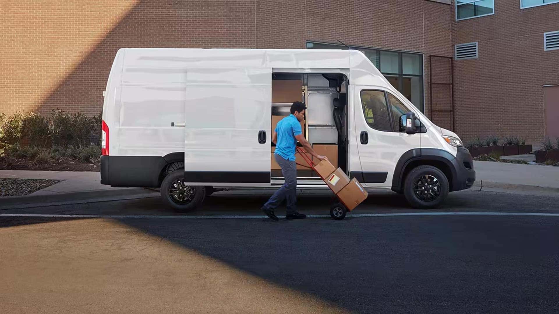 2026 RAM ProMaster Cargo Van with sliding side door open as worker unloads cargo boxes