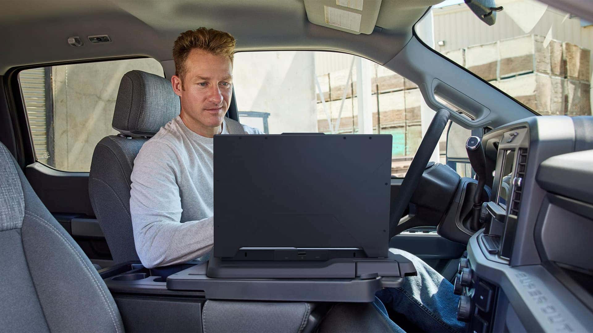 Driver using fold-down work surface inside the 2026 Ford F-350 Super Duty, showing mobile office functionality and interior workspace design