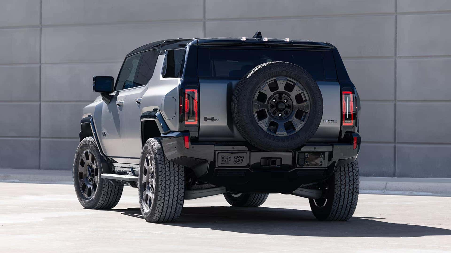 Rear angle of 2026 GMC HUMMER EV SUV showing taillights, rear-mounted spare tire, and rugged SUV design