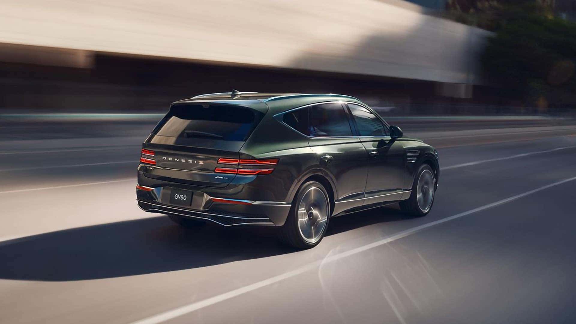 2026 Genesis GV80 driving at speed on a highway highlighting smooth performance and rear exterior design