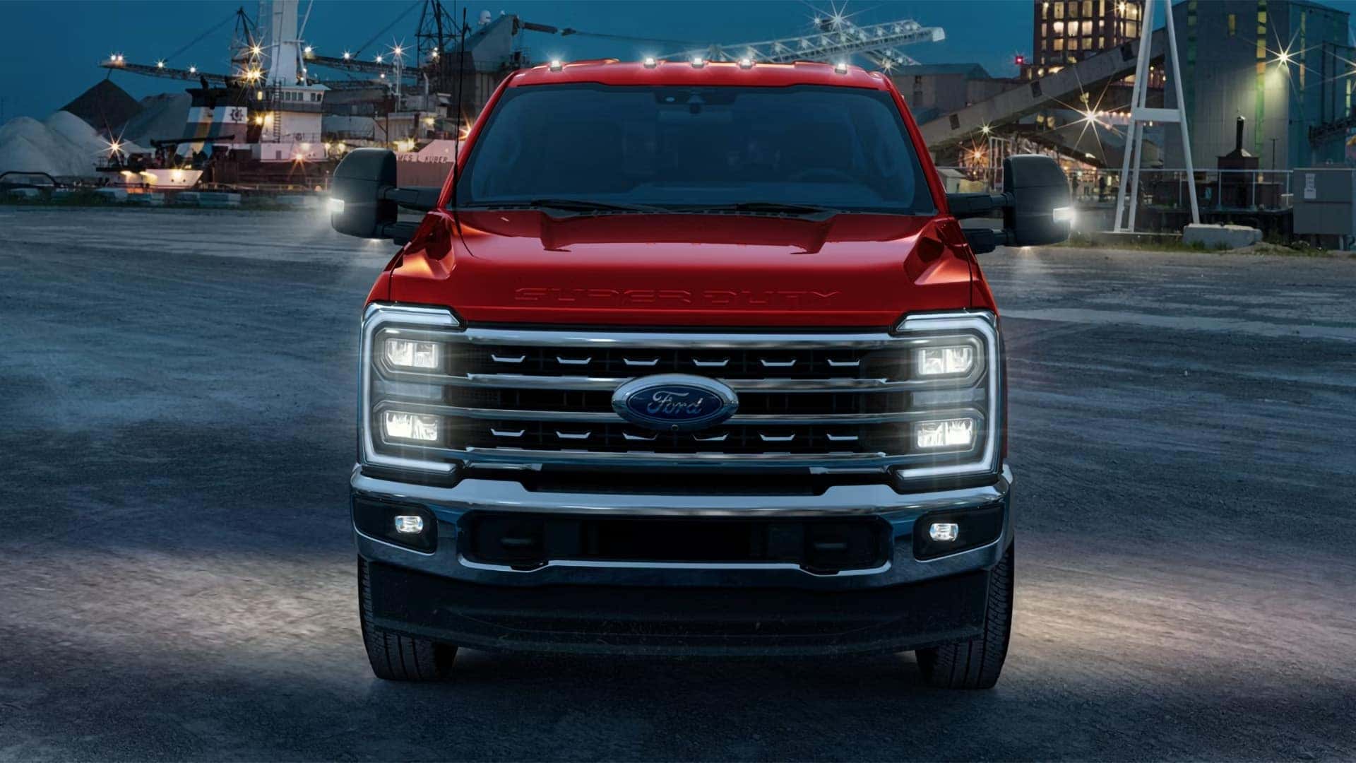 Front view of red 2026 Ford F-350 Super Duty at night with LED headlights and grille lighting illuminated