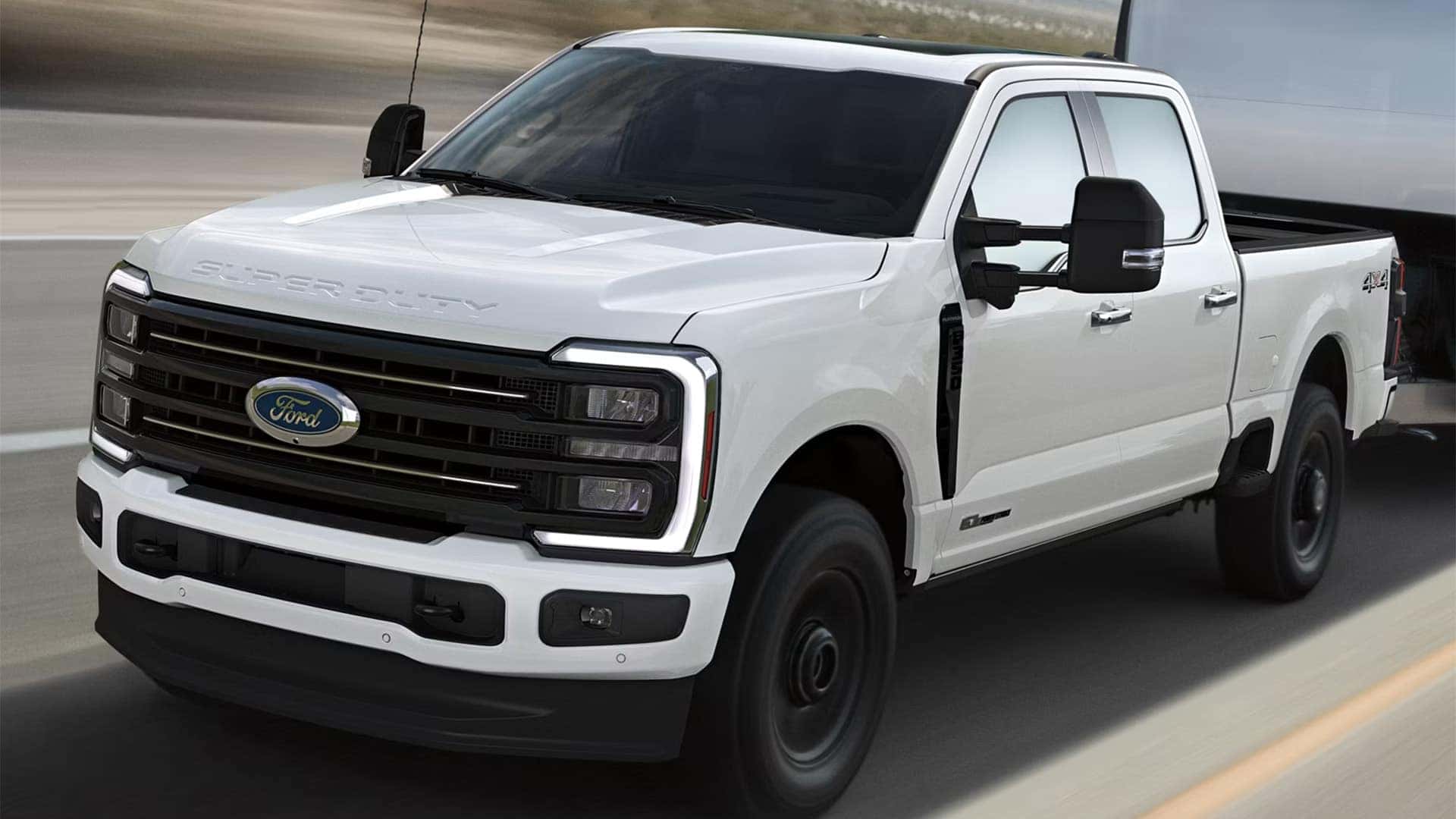 2026 Ford F-350 Super Duty driving while towing a large enclosed trailer on the highway