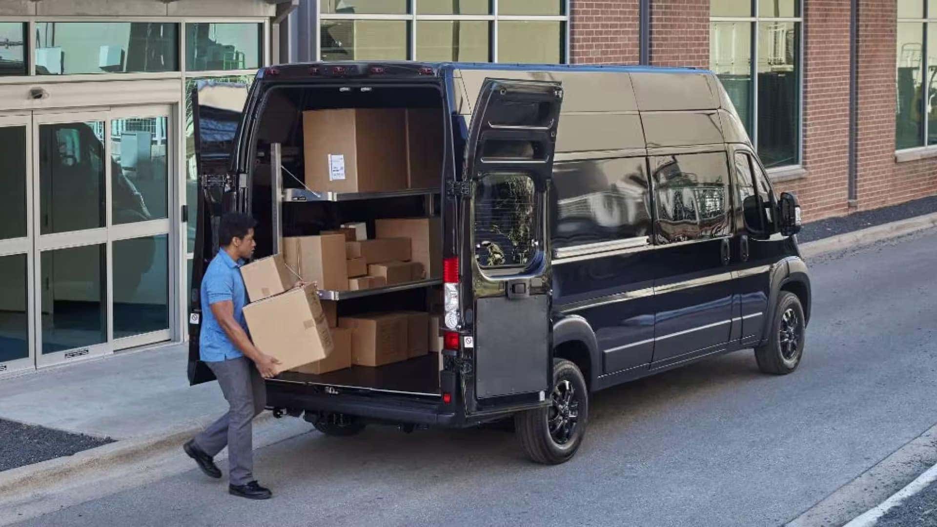 2026 RAM ProMaster Cargo Van with rear doors open as a worker unloads packages at a commercial building