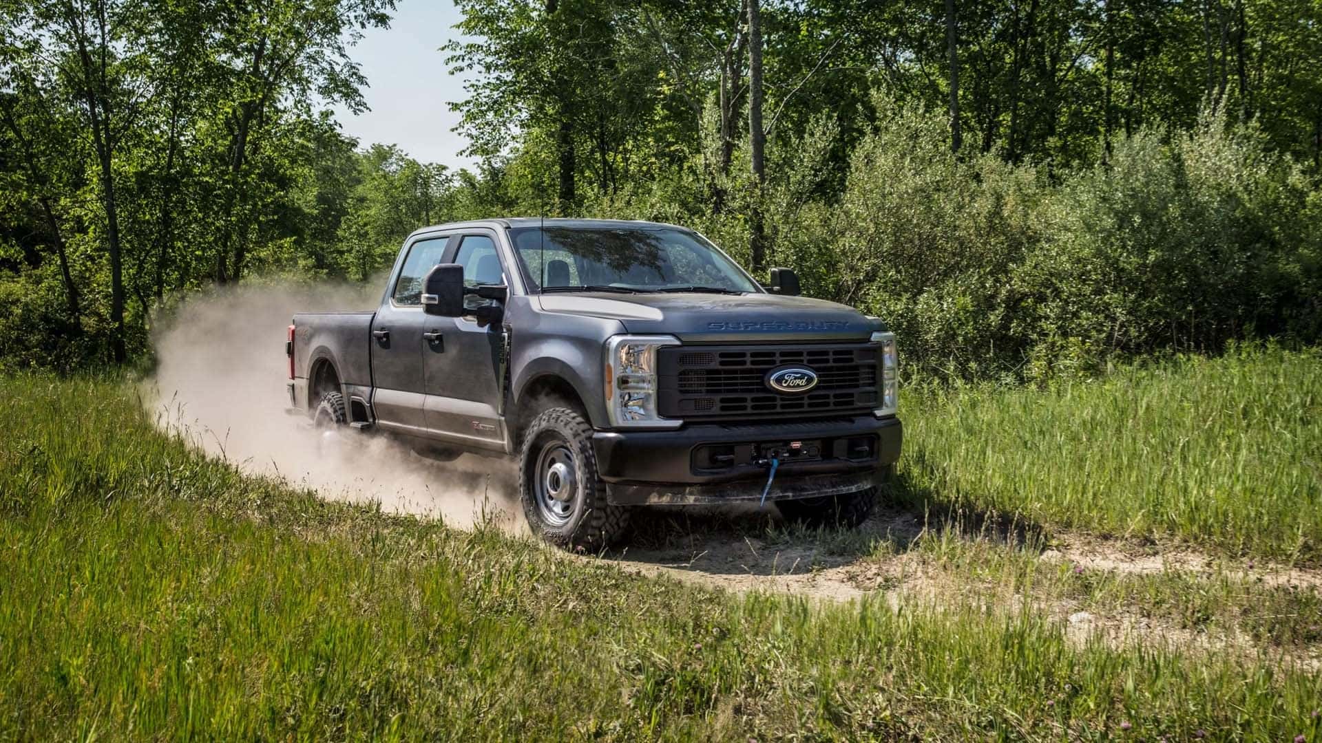 2026 Ford F-350 Super Duty driving through dirt terrain with dust trail, emphasizing off-road capability and heavy-duty performance