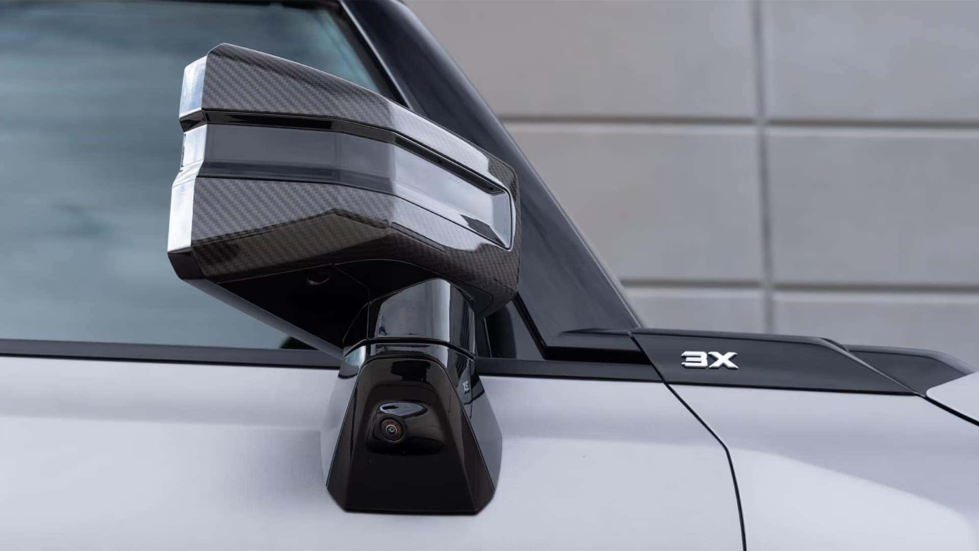 Close-up of 2026 GMC HUMMER EV SUV side mirror with carbon fiber detail and 3X trim badge