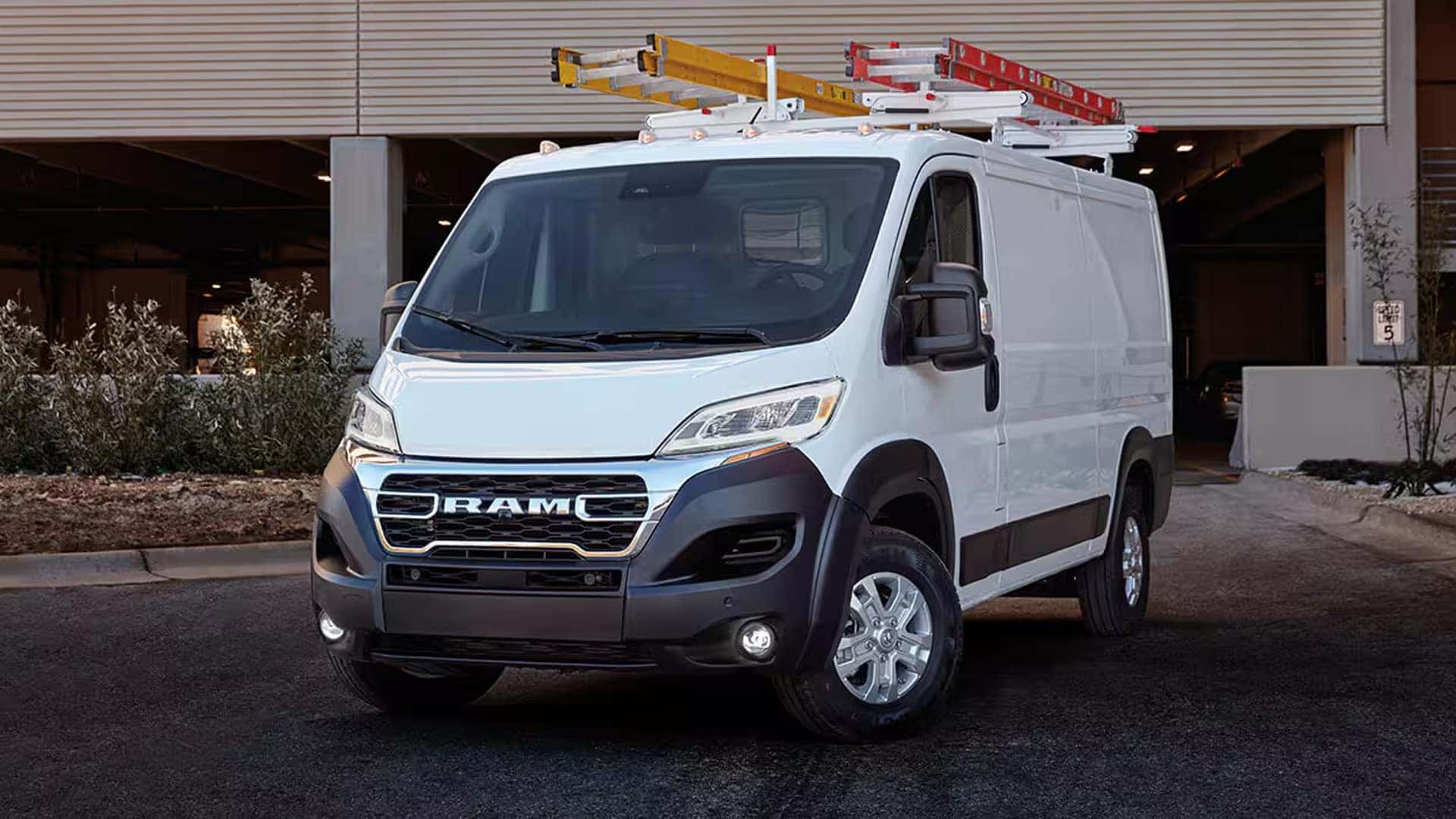 2026 RAM ProMaster Cargo Van parked outside a building with ladder rack and commercial upfit