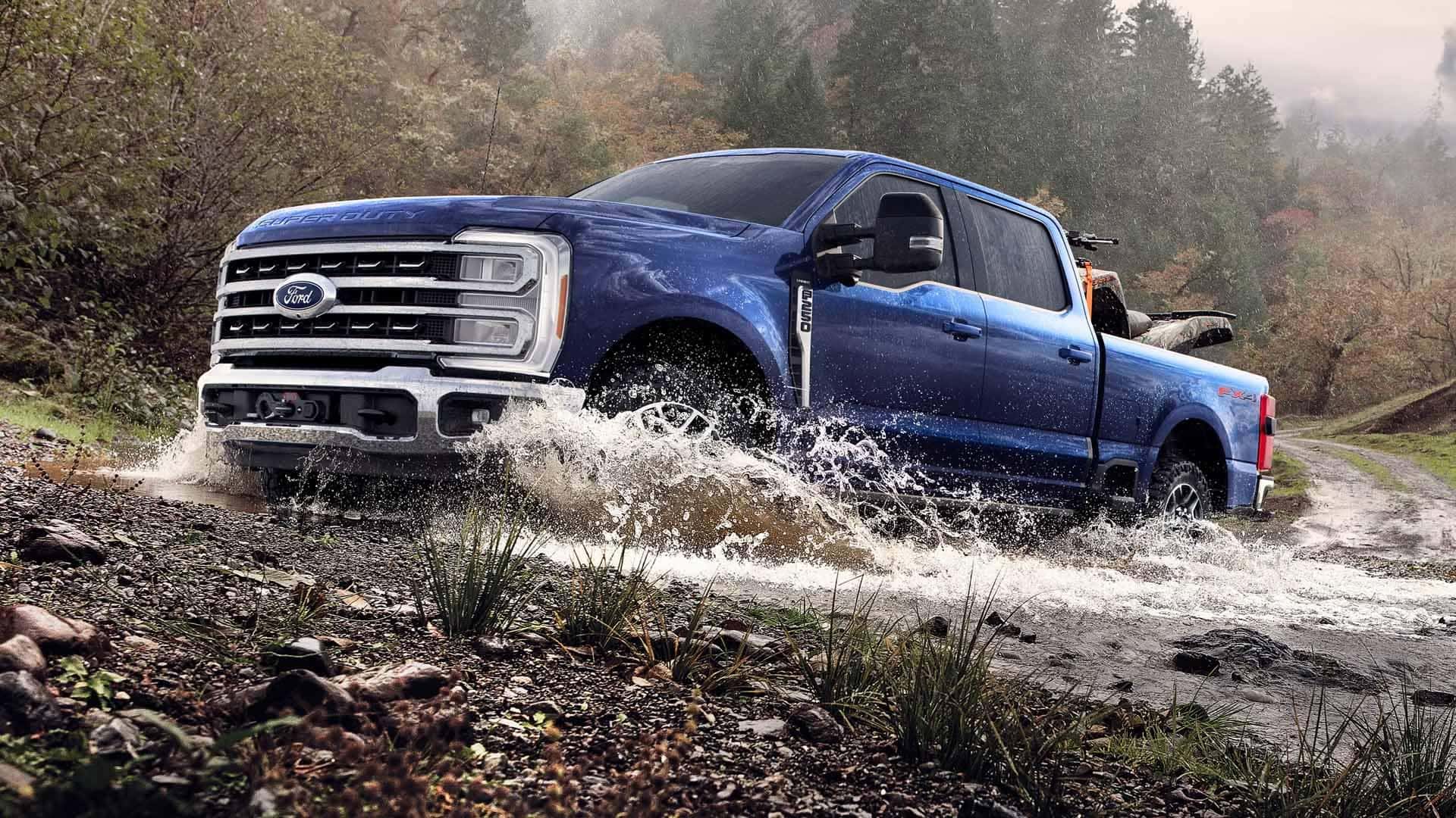 2026 Ford F-350 Super Duty driving through water on a rugged trail, highlighting truck durability, 4x4 capability, and bold exterior design