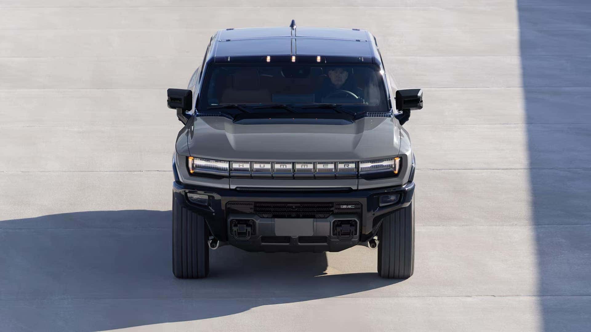 Front view of 2026 GMC HUMMER EV SUV driving on pavement showing exterior design and wide stance