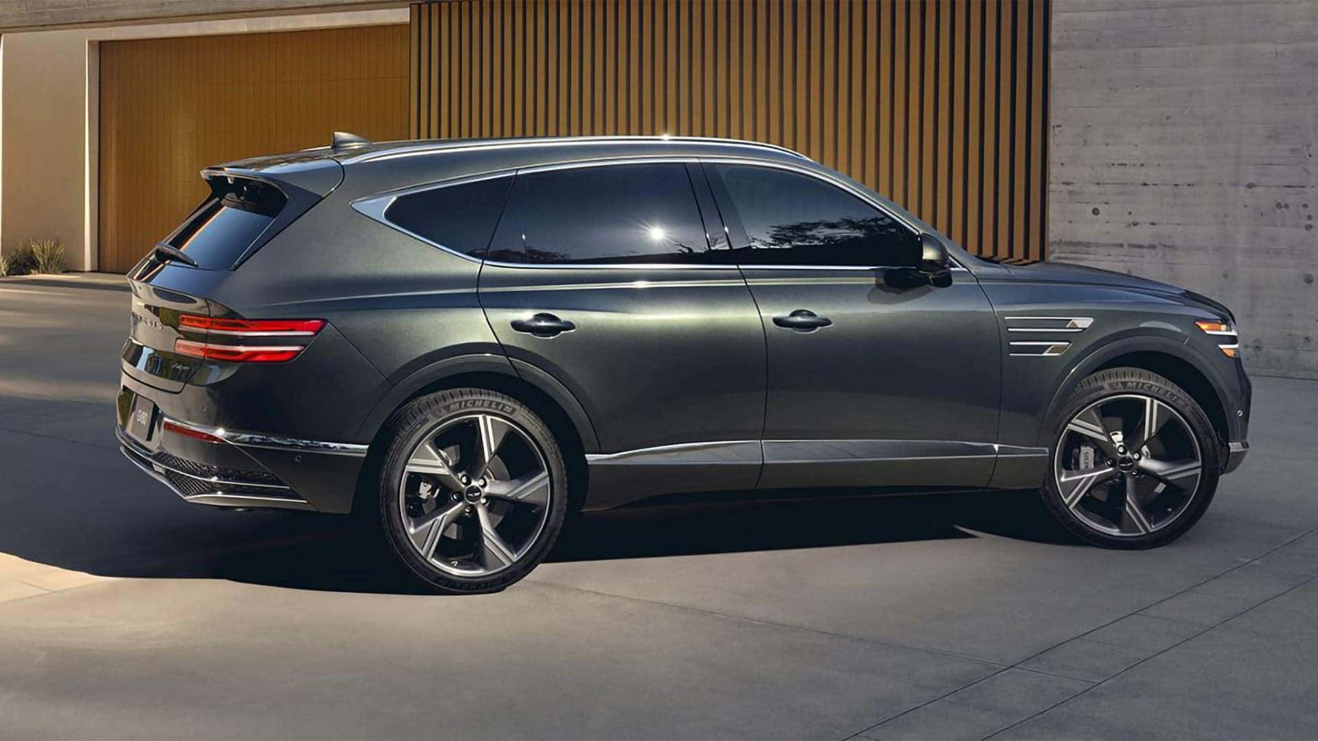 2026 Genesis GV80 driving at night with signature two line LED headlamps and illuminated front design